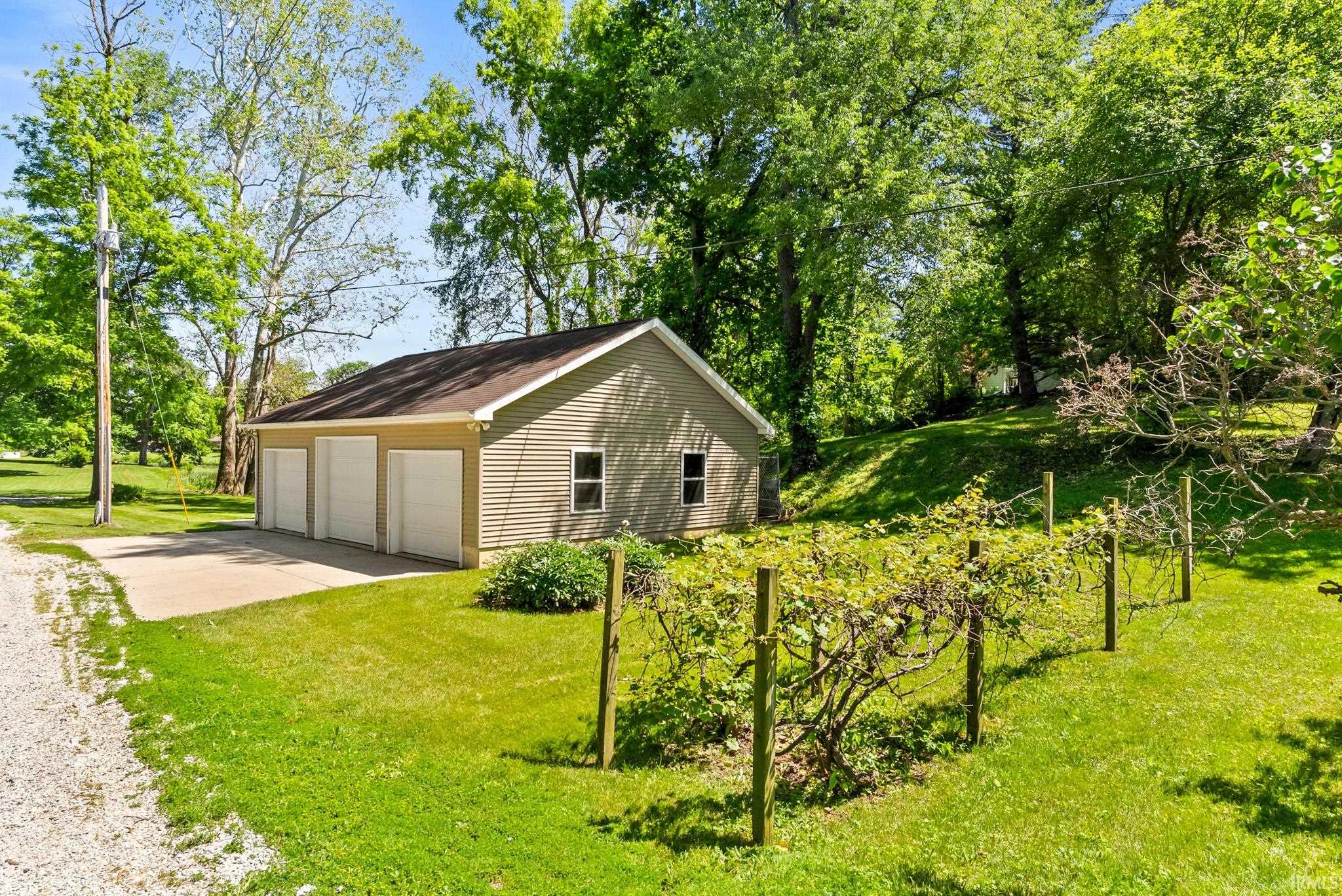Three-car garage with tan siding and white overhead doors