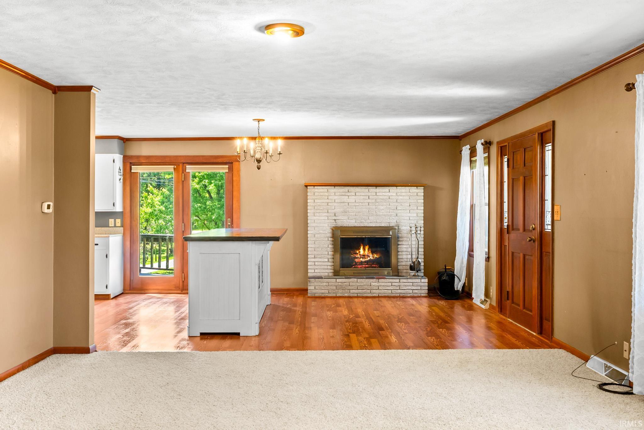 Living area featuring a brick fireplace with a wood mantel, hard surface flooring, and a chandelier