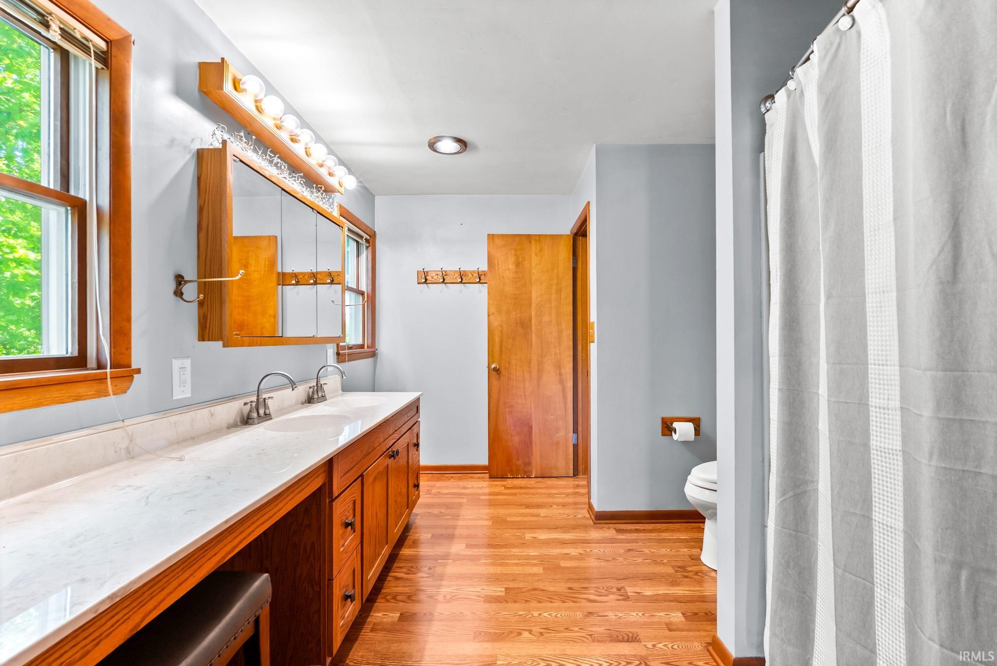 Bathroom featuring a double vanity with two sinks, a light-colored countertop, and wood-finish cabinetry