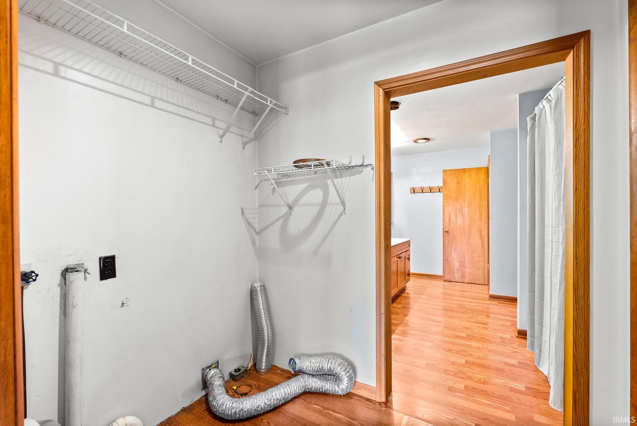 Dedicated utility space featuring wire shelving, wall outlets, and plumbing hookups