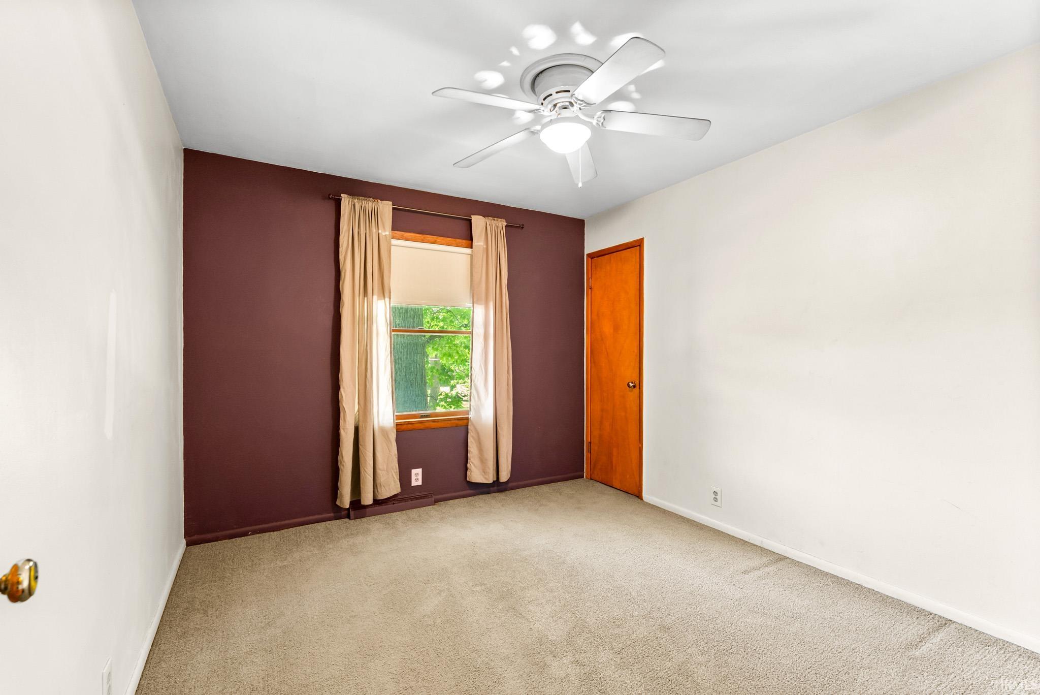 Room featuring light-toned carpeting and a window with wood trim