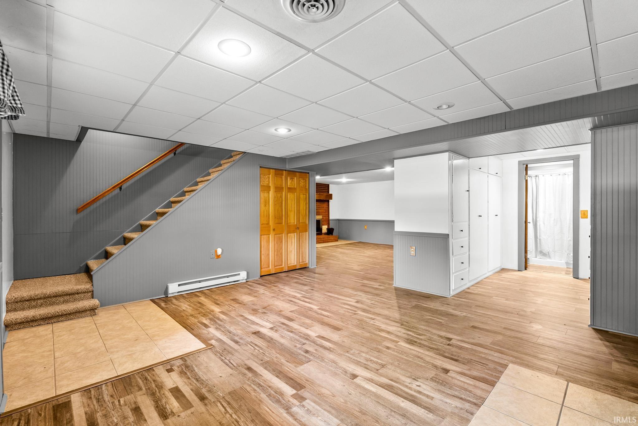 Finished lower level featuring wood-finish flooring, recessed lighting, and a drop ceiling