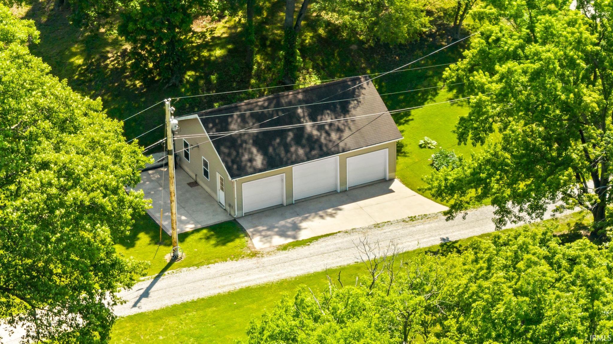 Detached three-car garage with light-colored siding and a dark shingle roof