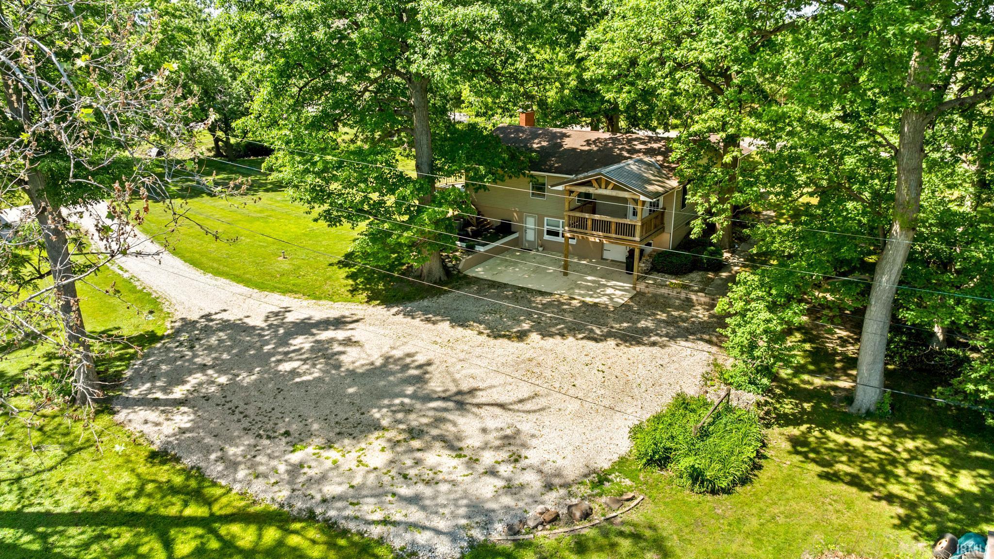 Two-story exterior with a covered porch featuring wooden railings and a gravel driveway