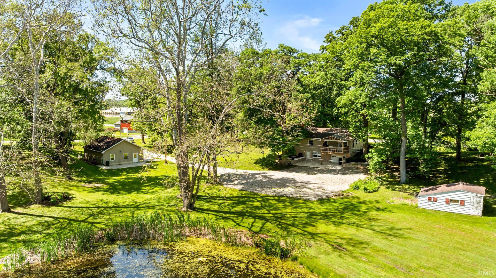 Expansive property featuring a tranquil pond, mature trees, and lush greenery