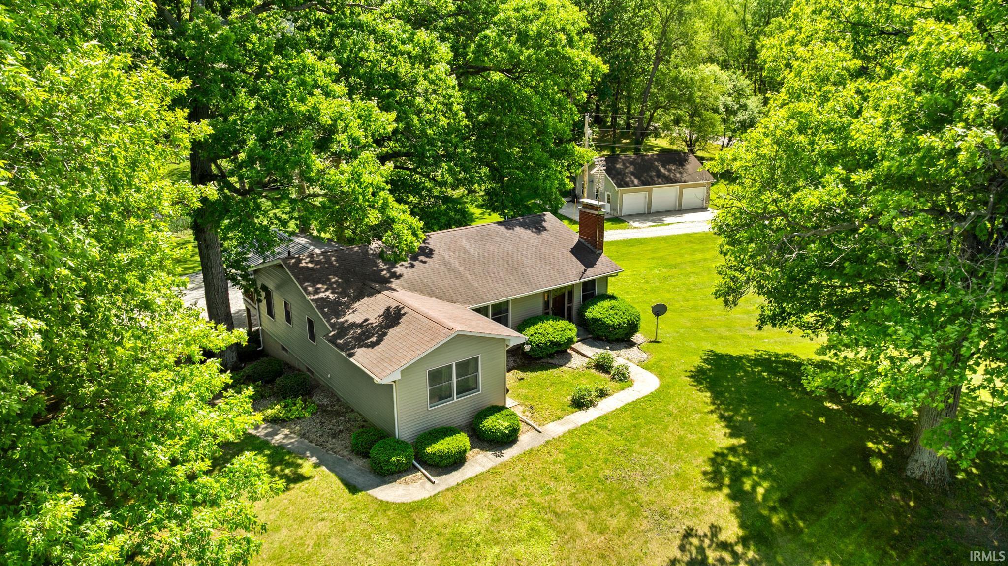 Ranch-style residence featuring a light gray exterior, a prominent brick chimney, and a brown shingle roof