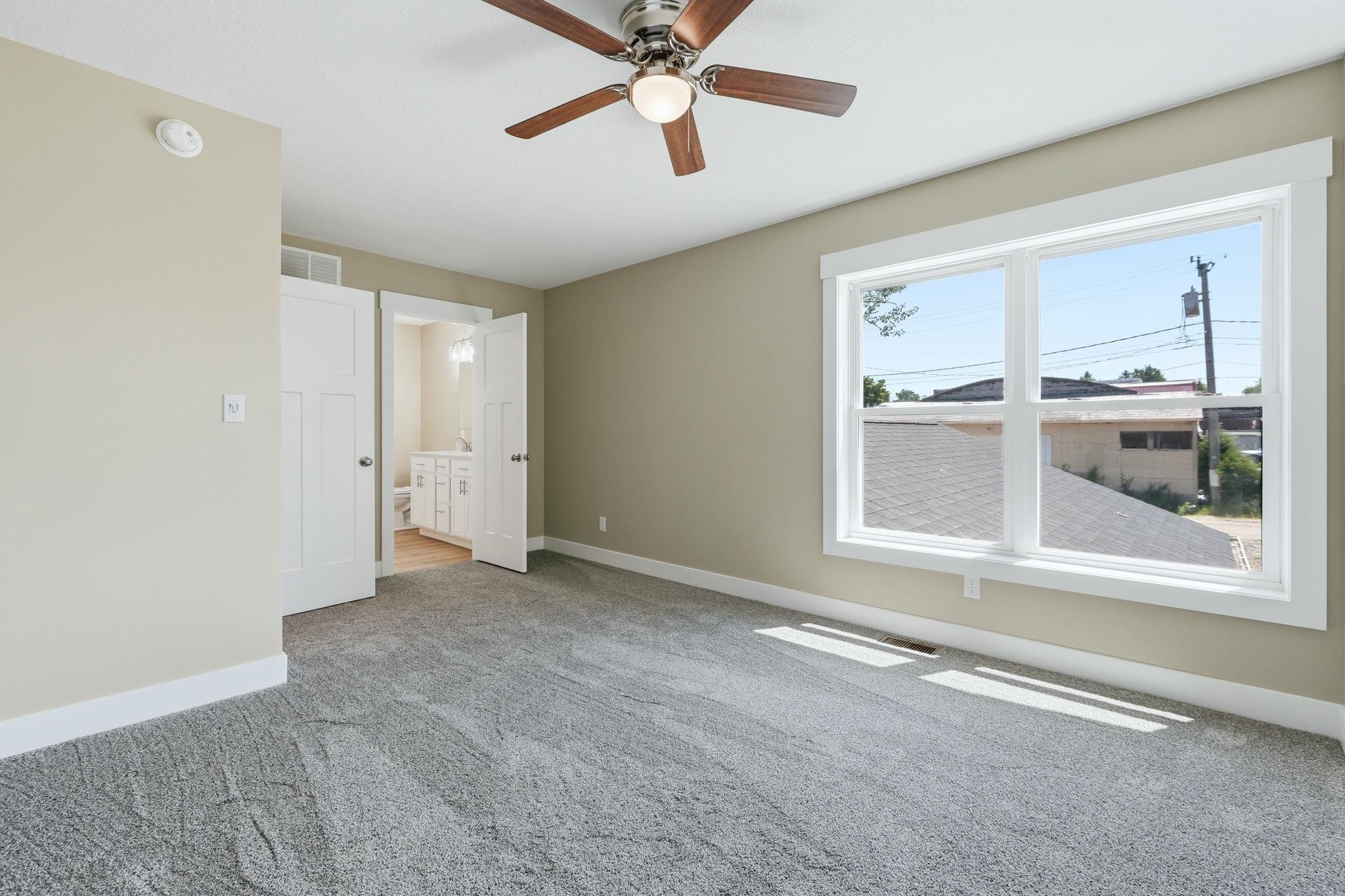 Spacious room featuring neutral carpeting, a dual-pane window with white trim, and light beige walls