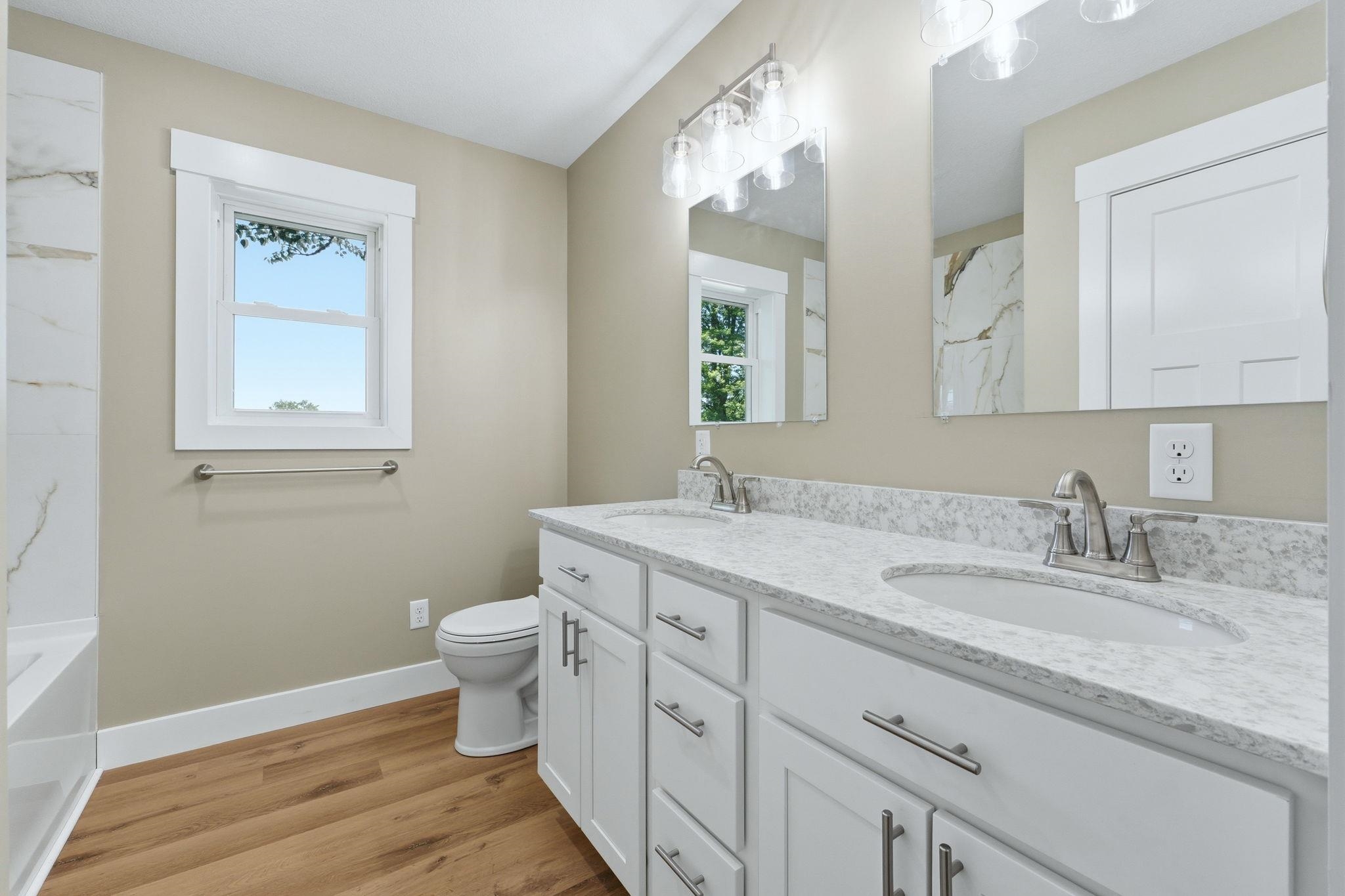 Dual vanity featuring white shaker cabinetry, brushed nickel hardware, and a stone-finish countertop with integrated sinks