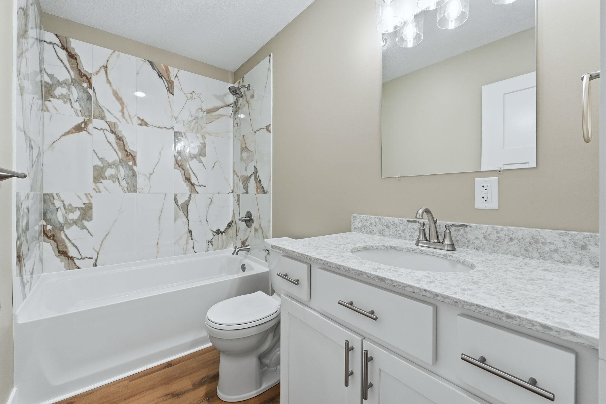 Bathroom featuring a white vanity with a light-colored countertop, an integrated sink, and white cabinetry with brushed nickel hardware