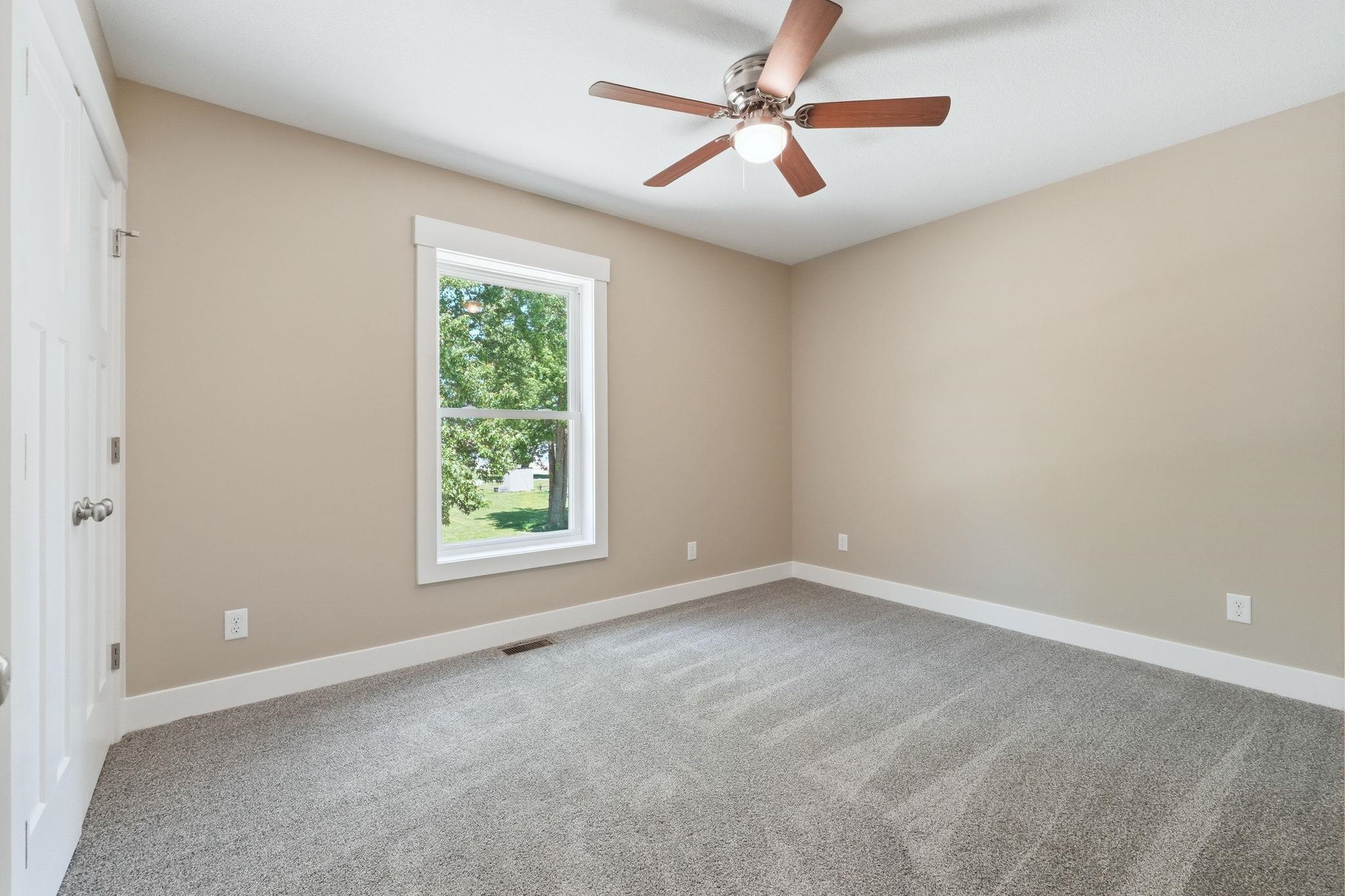 Carpeted room with a ceiling fan, a single window, and a white door with silver hardware