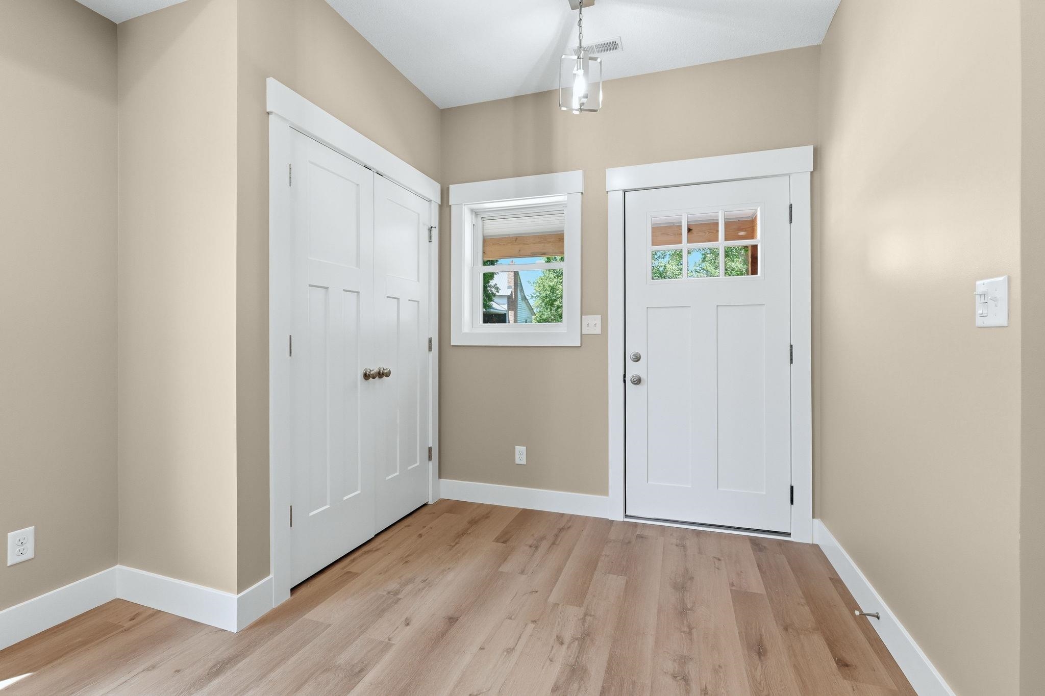 Entryway featuring a white paneled door with glass inserts, light wood-finish flooring, and a double-door closet