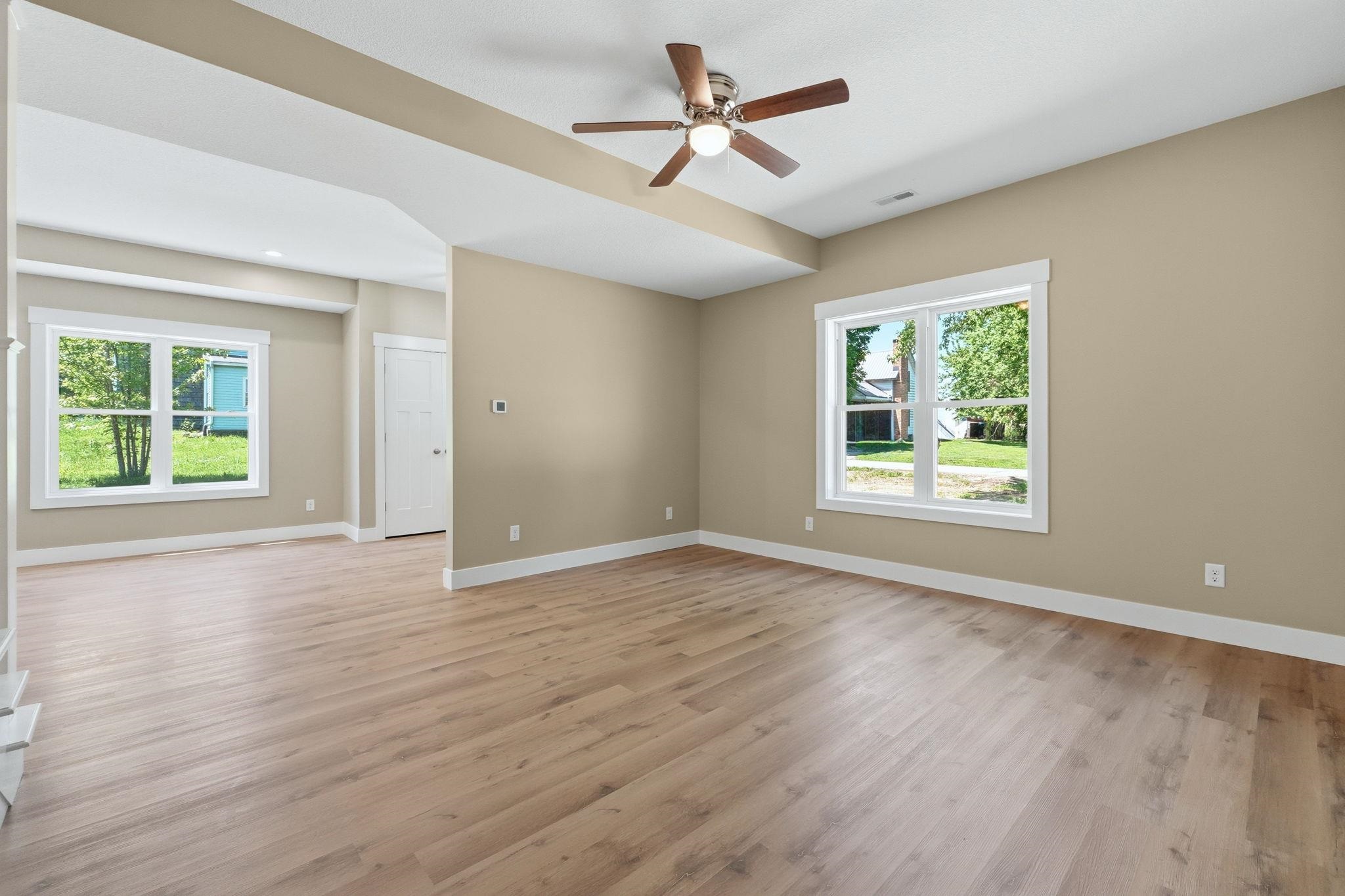 Spacious room featuring wood-finish flooring, neutral-toned walls, and abundant natural light from multiple windows