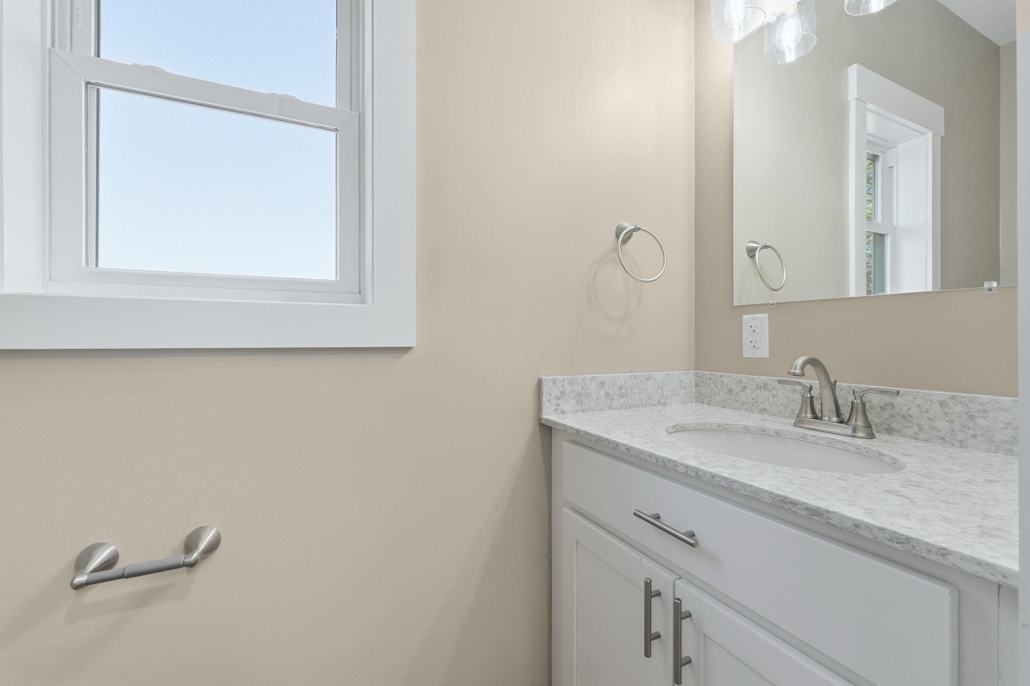 Bathroom vanity featuring white cabinetry with brushed nickel hardware, a light-toned countertop, and an undermount sink