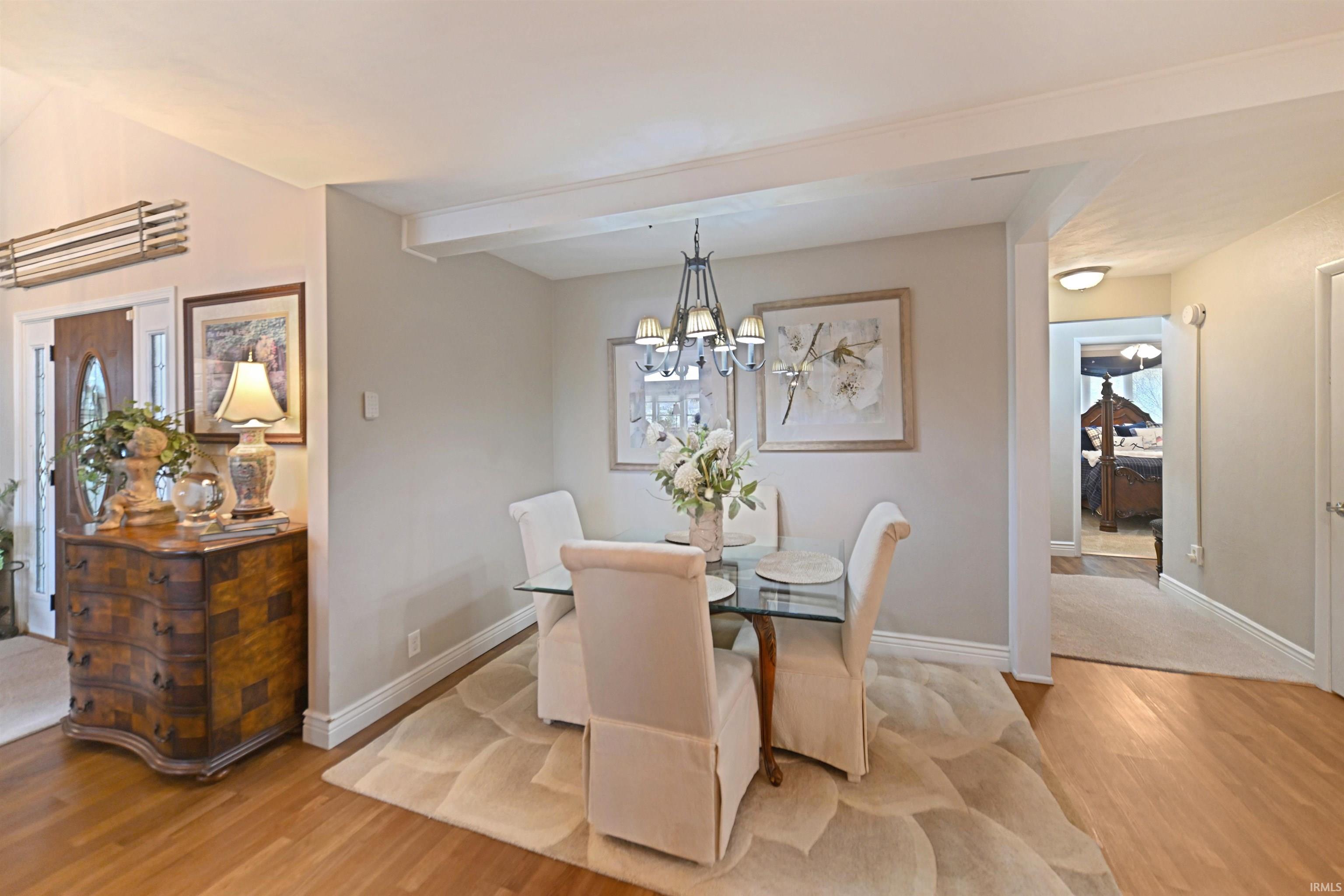 Dining area featuring a glass-top table, chandelier lighting, and a neutral area rug