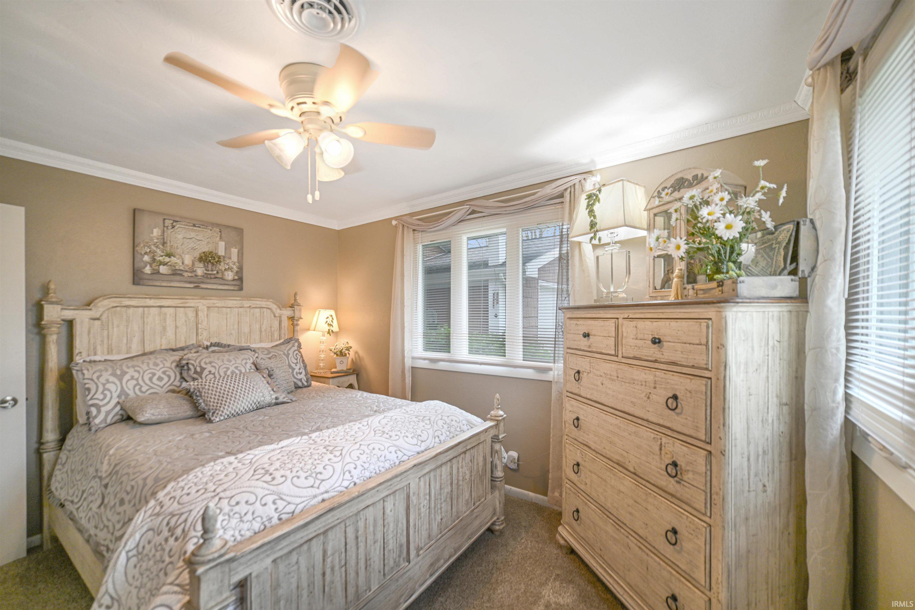 Carpeted room featuring a ceiling fan with integrated lighting, crown molding, and neutral wall paint
