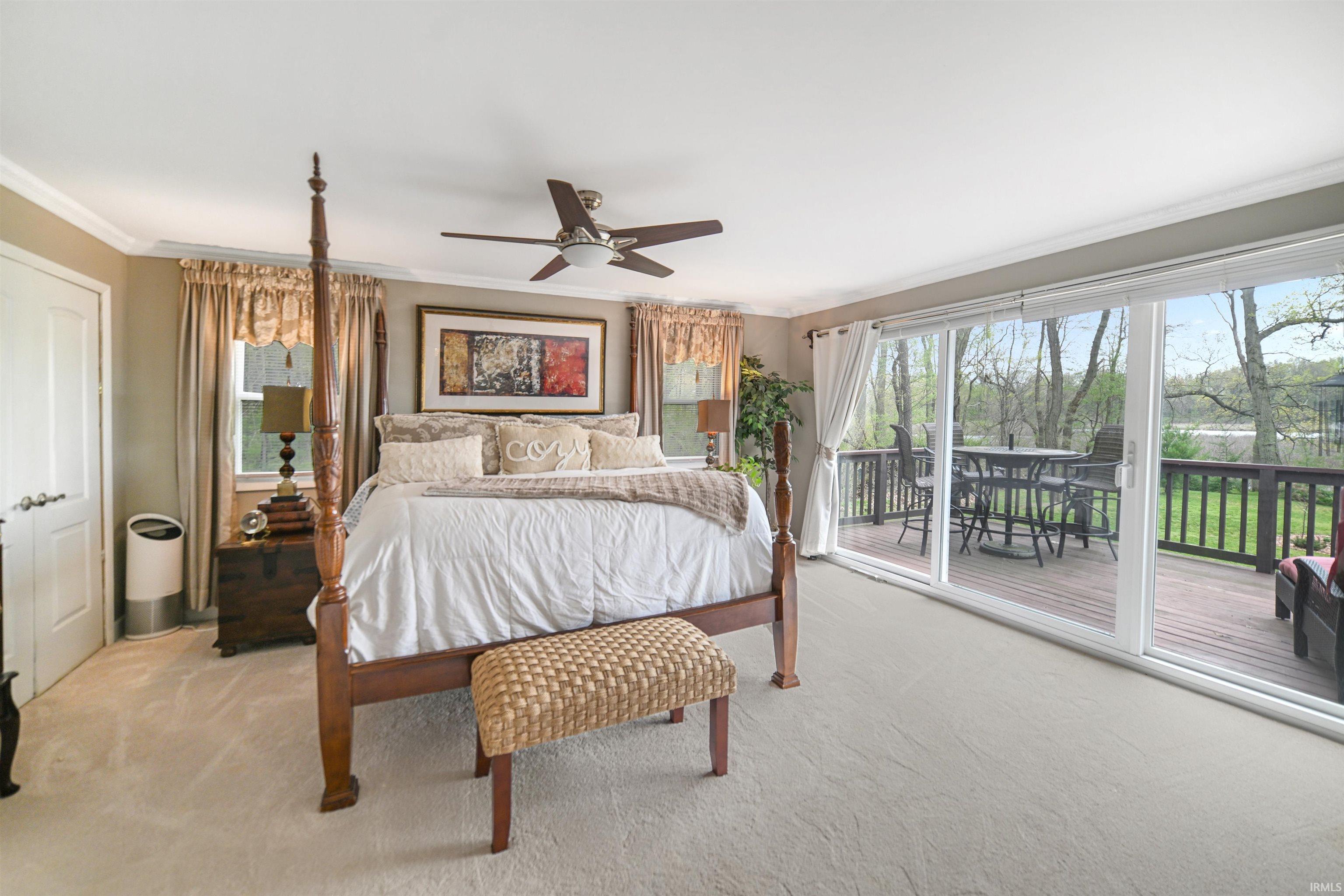 Carpeted room with a ceiling fan, crown molding, and sliding glass doors leading to a private outdoor deck