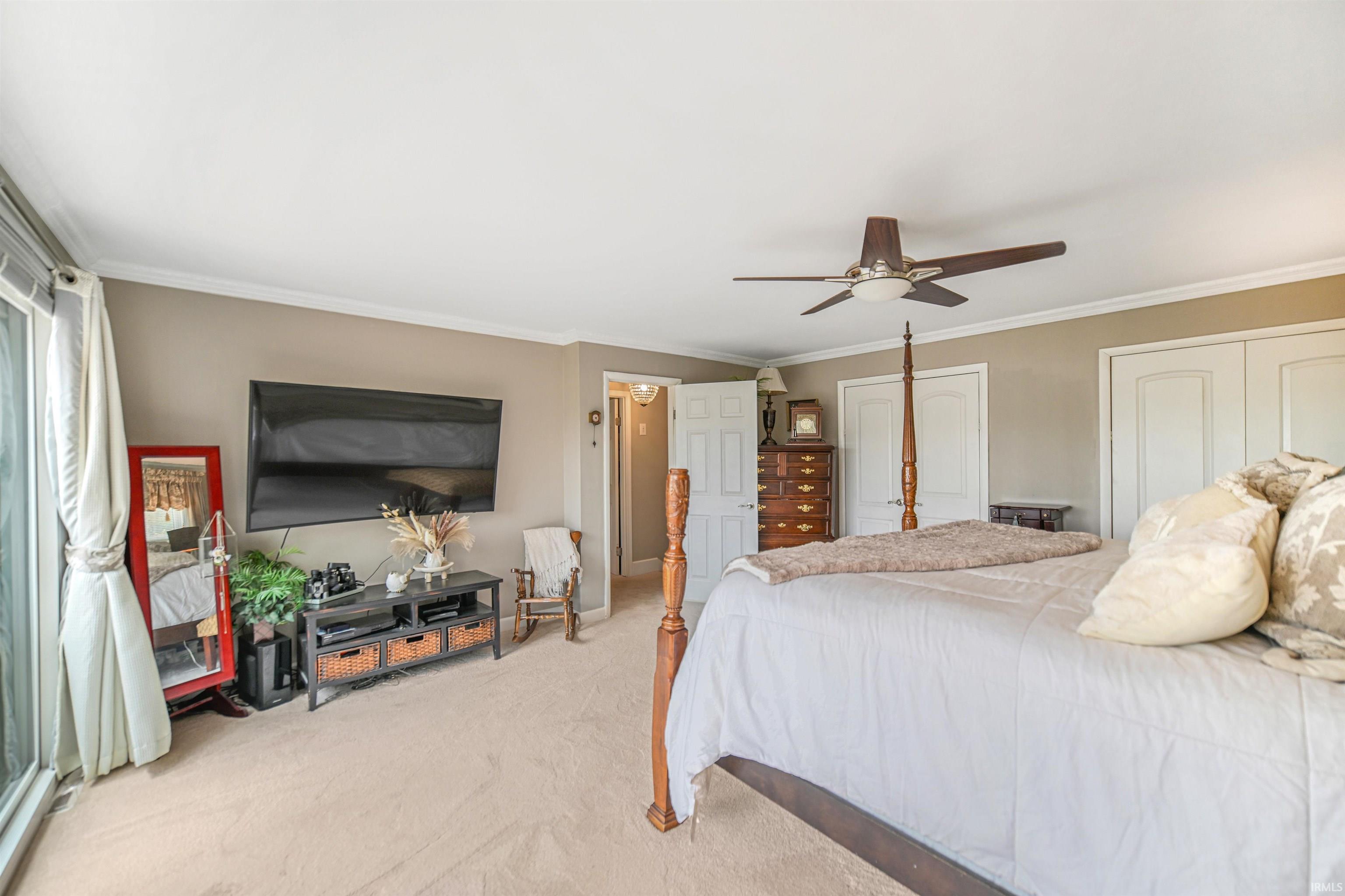 Carpeted room featuring a ceiling fan, crown molding, and a sliding glass door