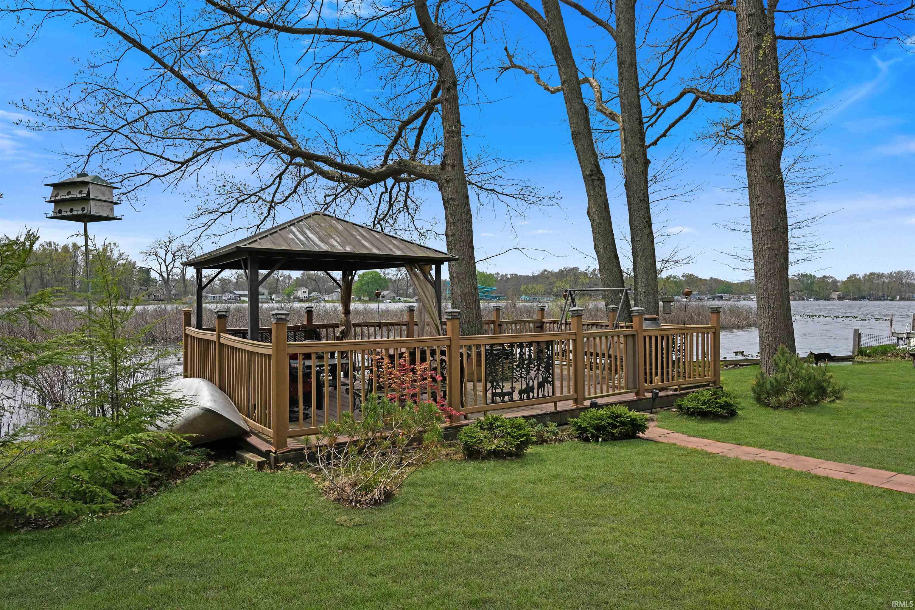 Lakeside wooden deck featuring a metal-roofed gazebo and spindle railings