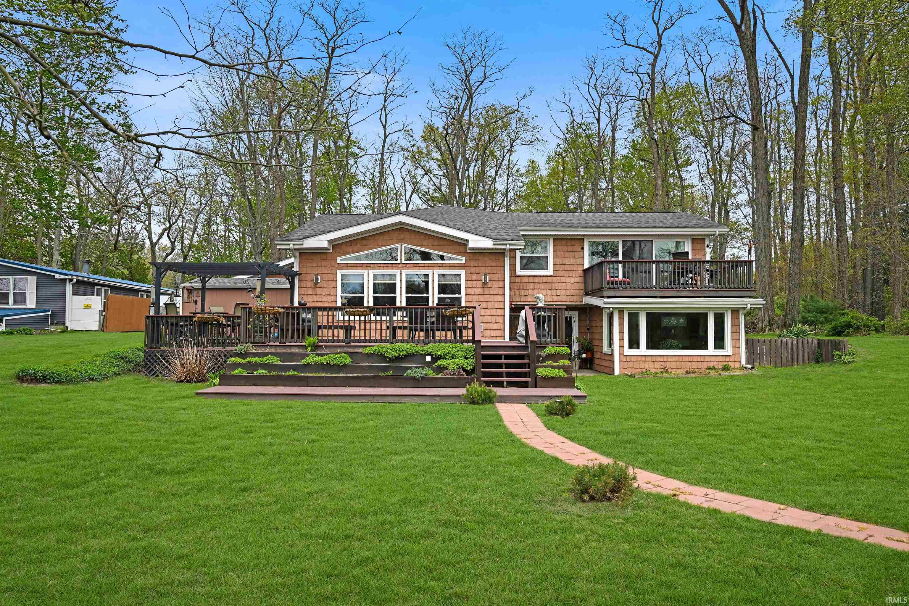 Shingle-sided residence featuring multiple outdoor entertaining areas, including a two-tier deck with integrated planters and a second-story balcony