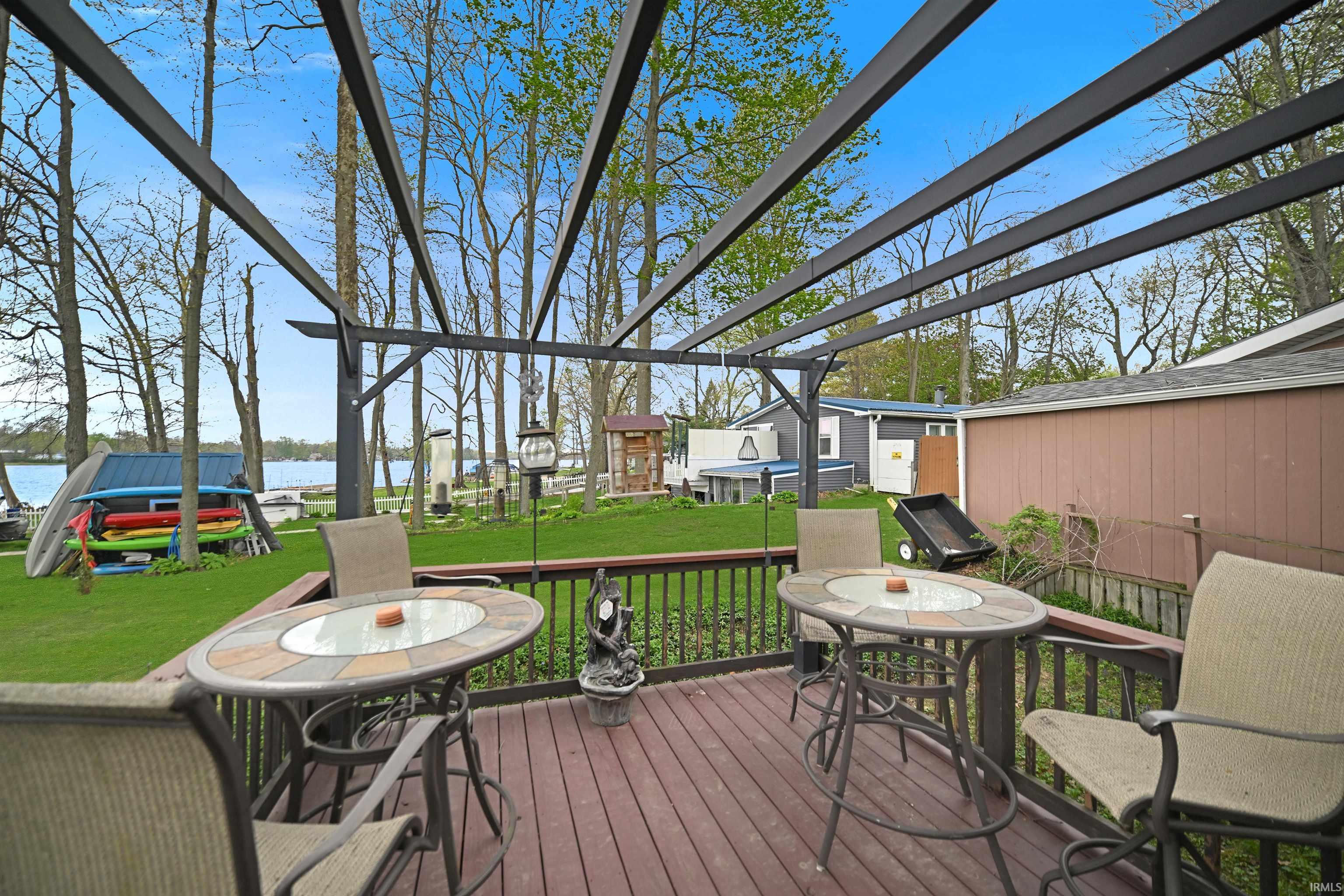 Expansive wood-finish deck featuring a slatted railing and overhead pergola structure