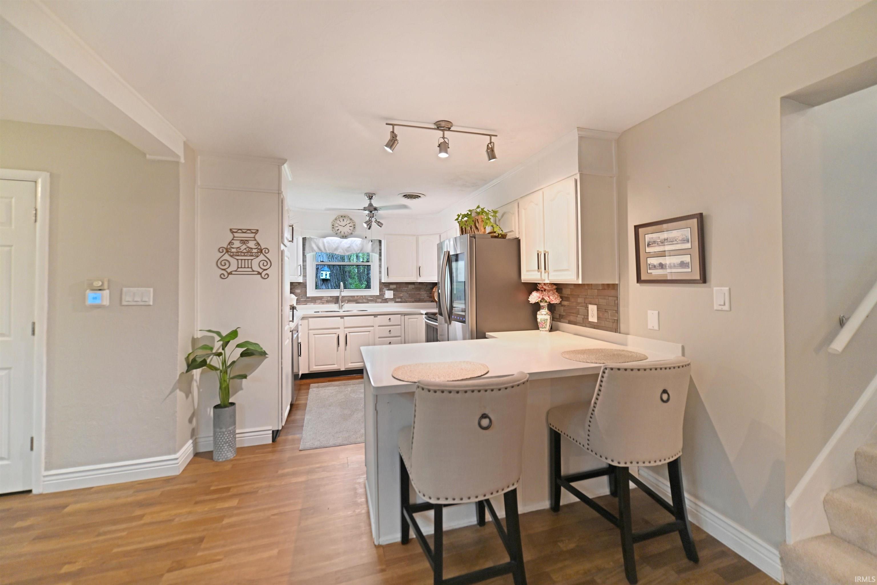 Kitchen featuring white cabinetry, a counter-height breakfast bar, stainless steel appliances, and wood-finish flooring