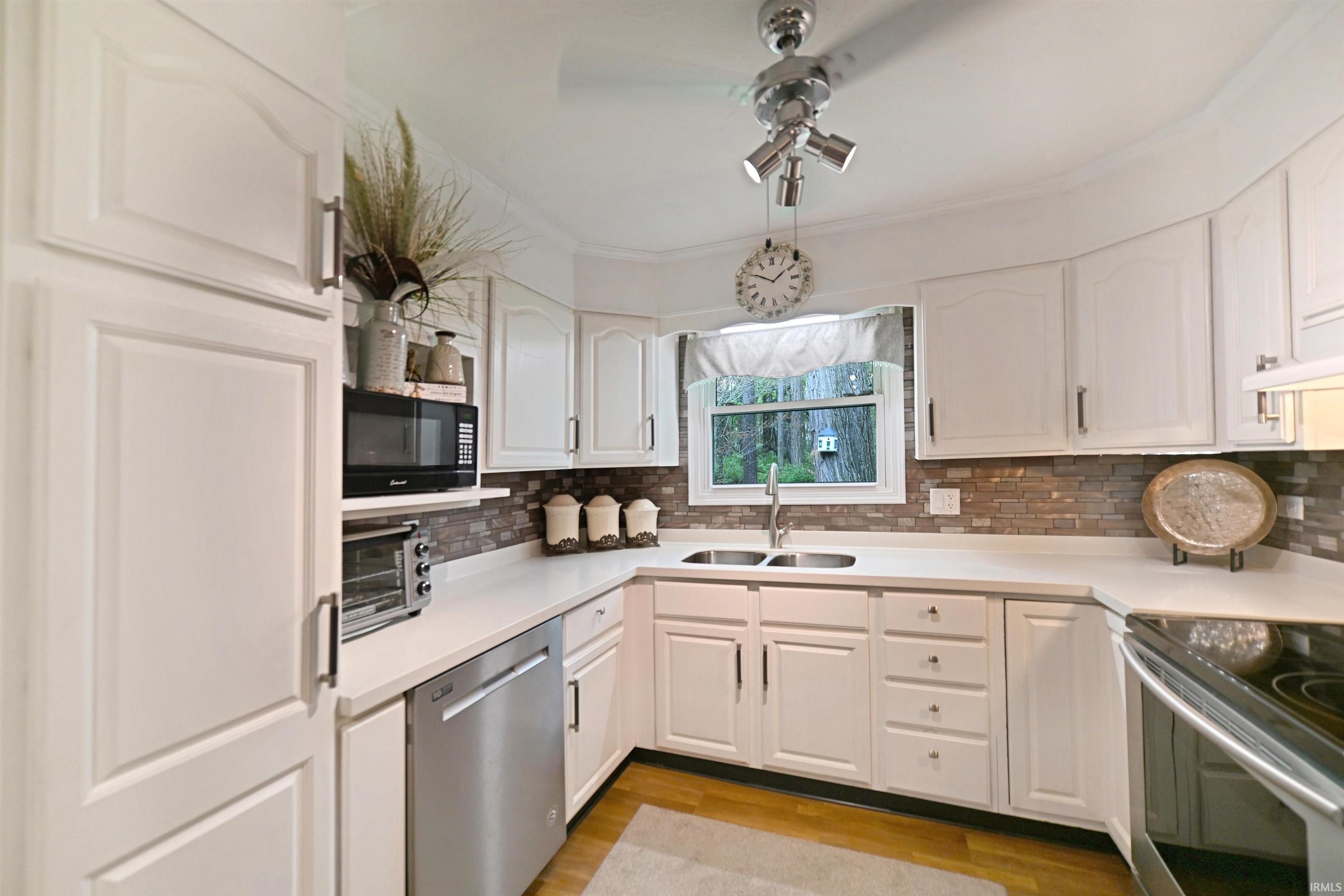 Kitchen featuring white cabinetry with silver hardware, light countertops, and a stone-look tile backsplash