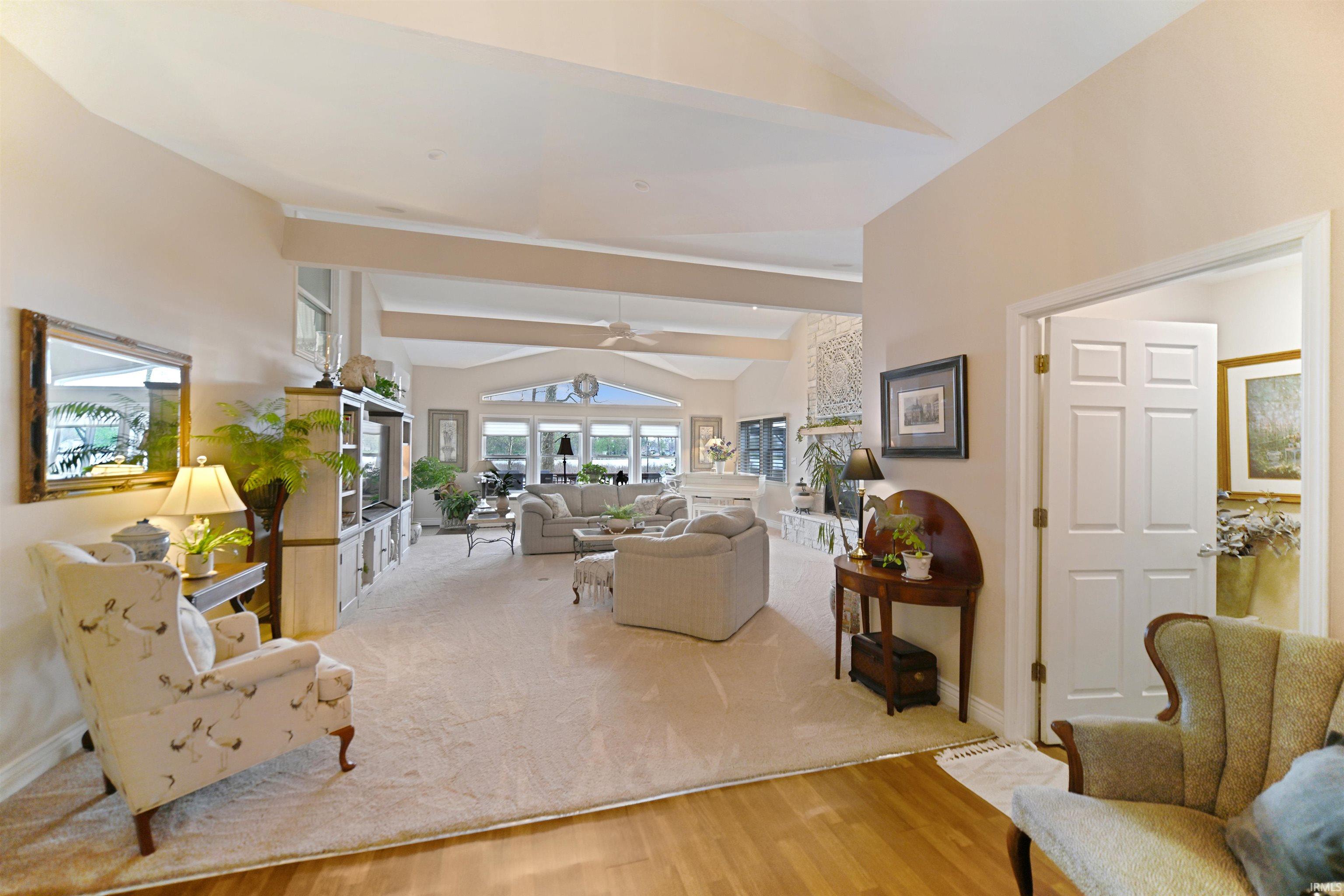 Expansive living space featuring a vaulted ceiling with exposed beams, large windows, and an arched transom window