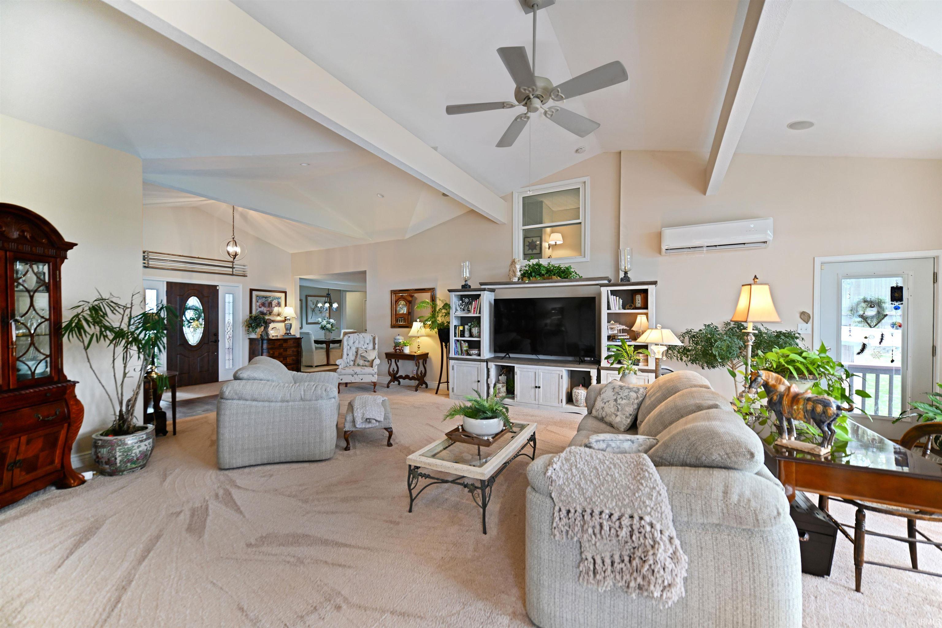 Spacious living area featuring a vaulted ceiling with exposed beams, ceiling fan, and recessed lighting