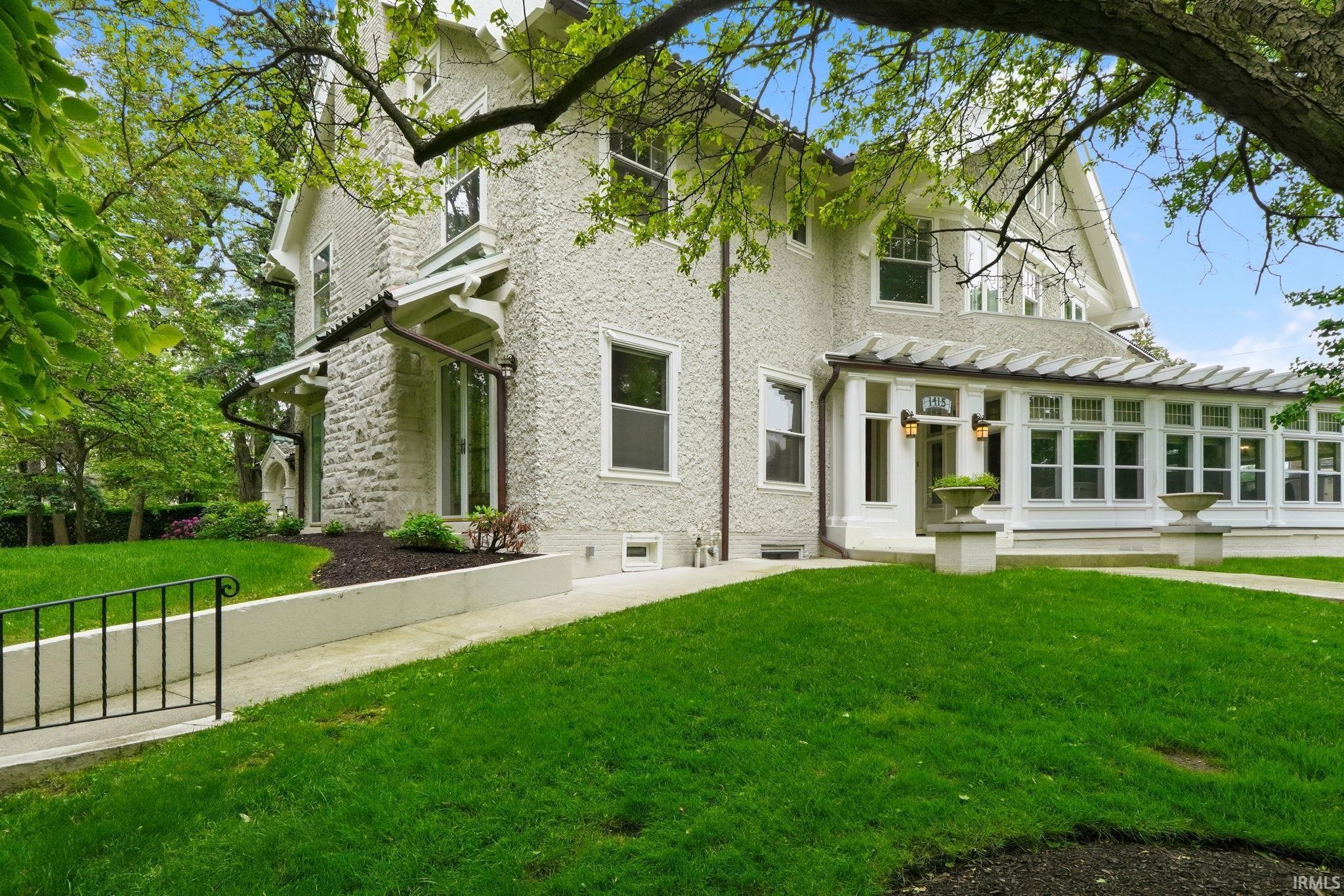Stucco and stone exterior with a prominent sunroom featuring multiple windows