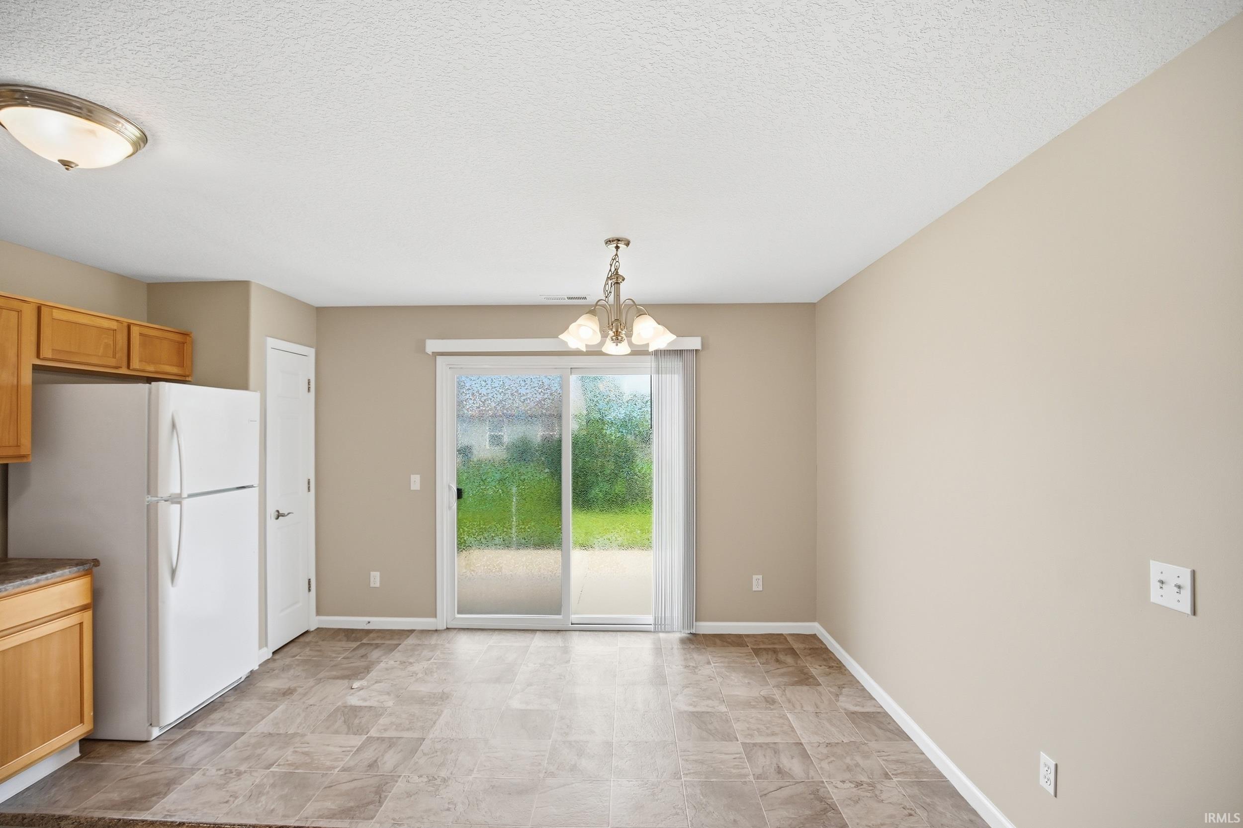 Dining area featuring sliding glass doors with outdoor access, neutral-toned walls, and tile flooring
