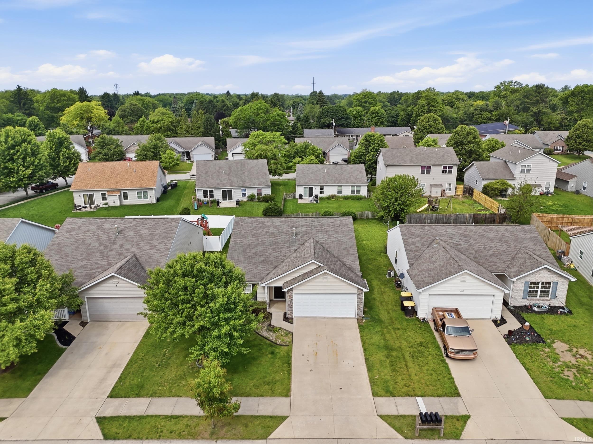 Residential neighborhood with established homes featuring neutral siding exteriors, attached garages, and mature landscaping