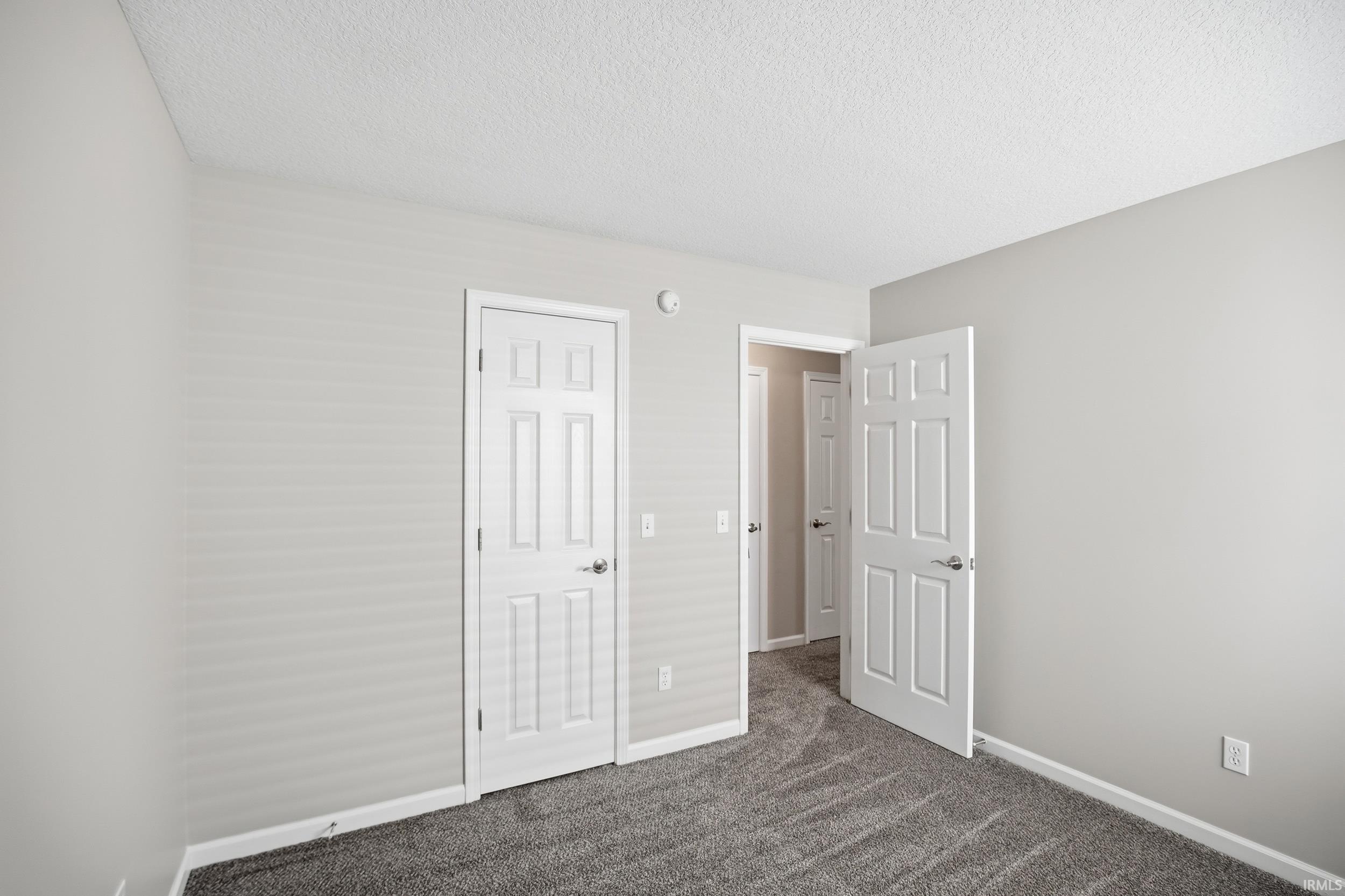 Interior room featuring light gray wall paint and textured carpet flooring