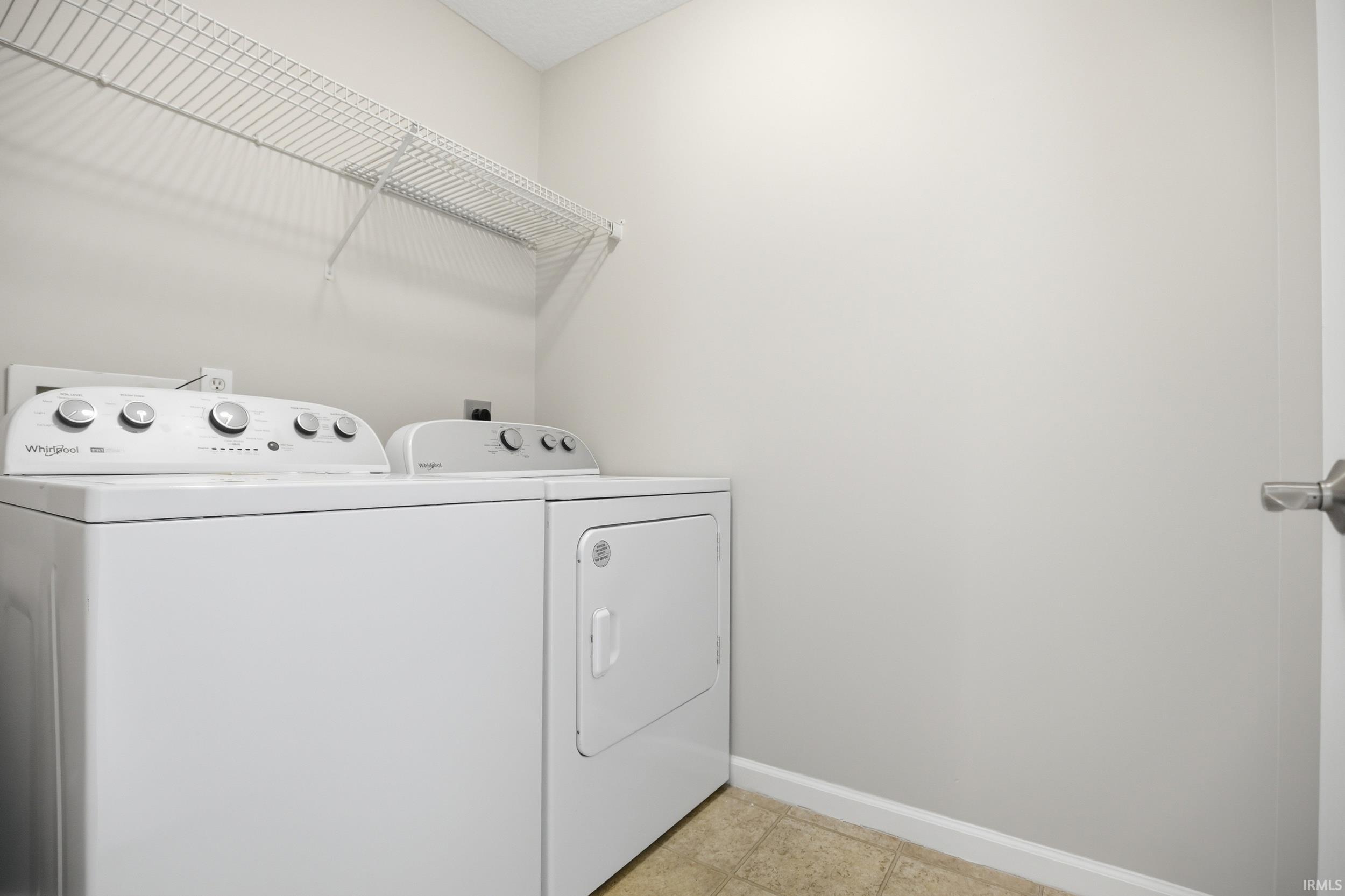 Dedicated laundry area featuring a white top-load washer, a white front-load dryer, and an overhead wire shelving unit