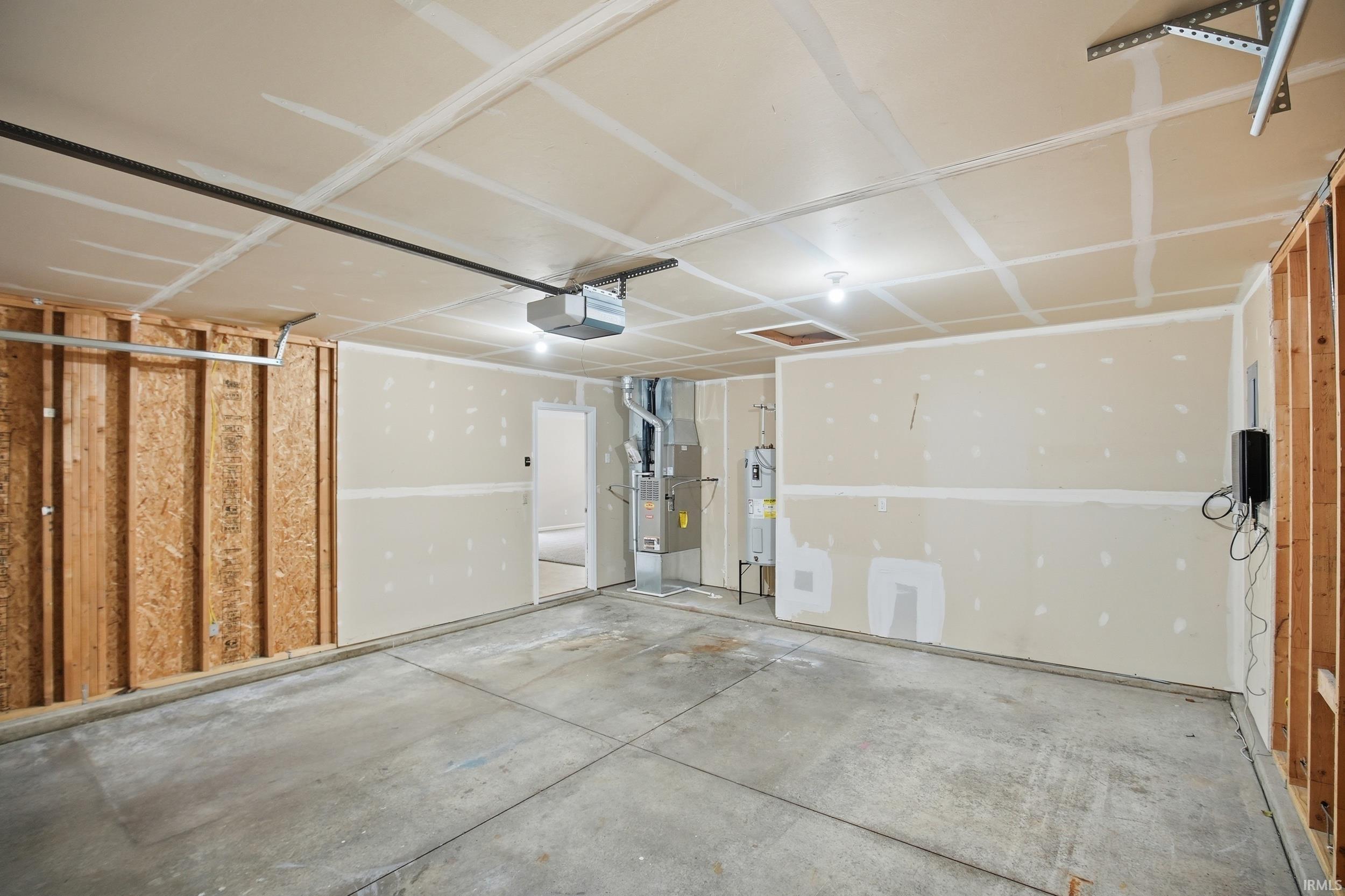 Spacious garage featuring a concrete floor, exposed wood framing, and an automatic garage door opener