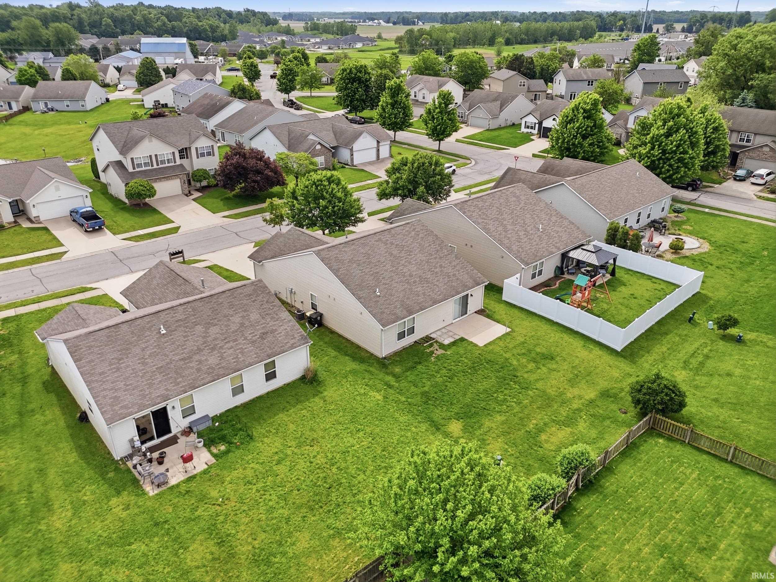 Aerial view showcasing a residential neighborhood with single-story and two-story homes featuring neutral siding and asphalt shingle roofs