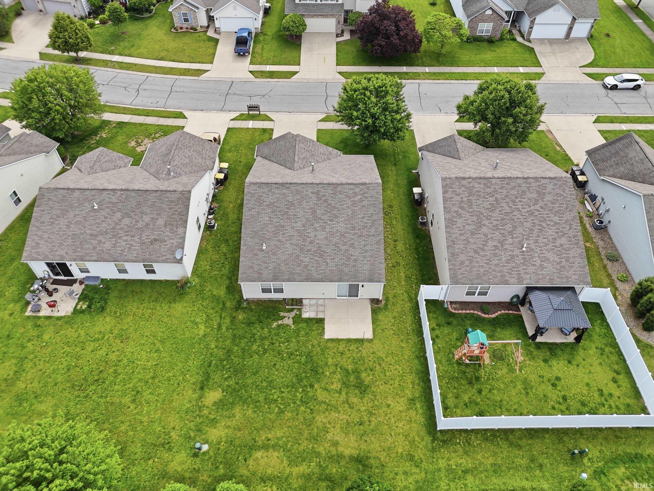 Expansive green lawn surrounds the property, featuring a concrete patio and a partial white privacy fence