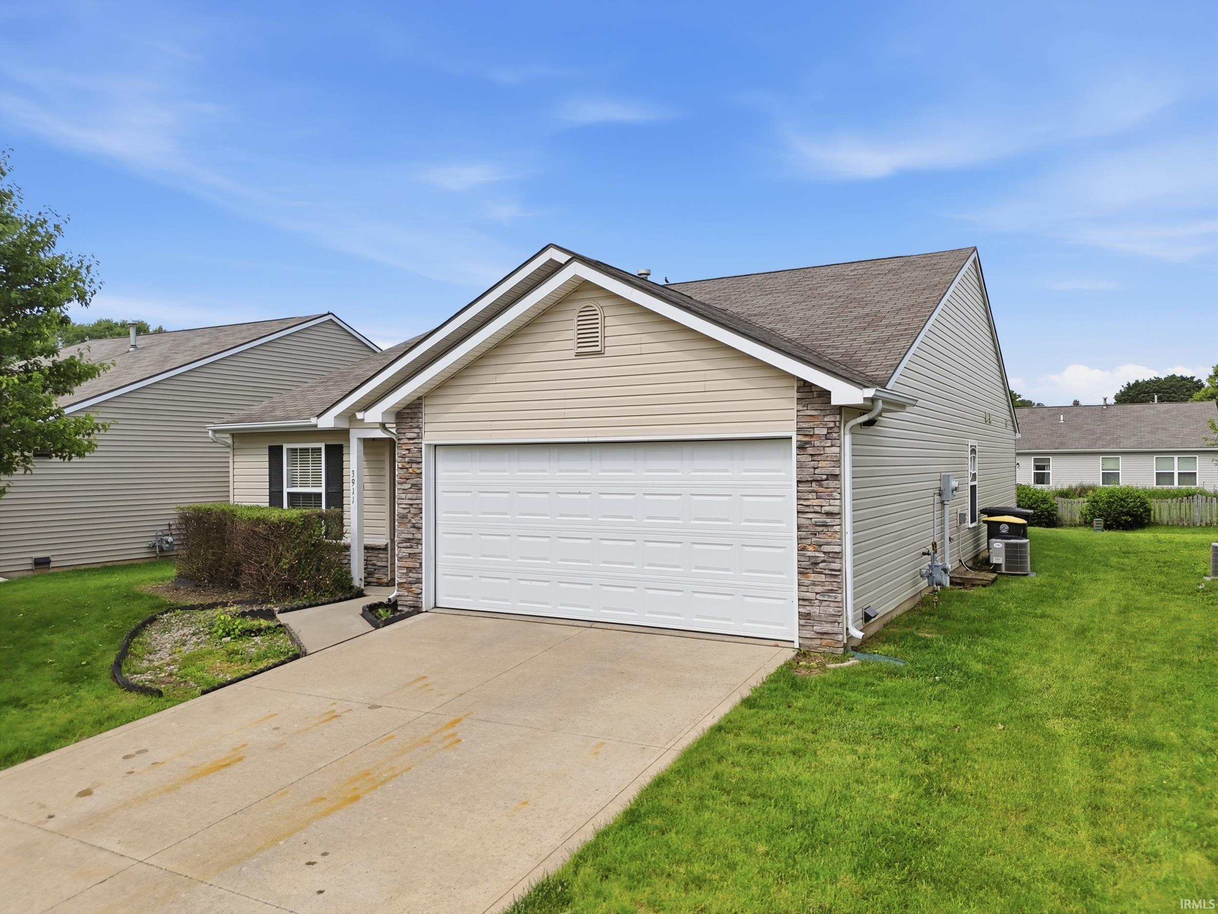 Single-story residence featuring a concrete driveway and an attached garage with a segmented door