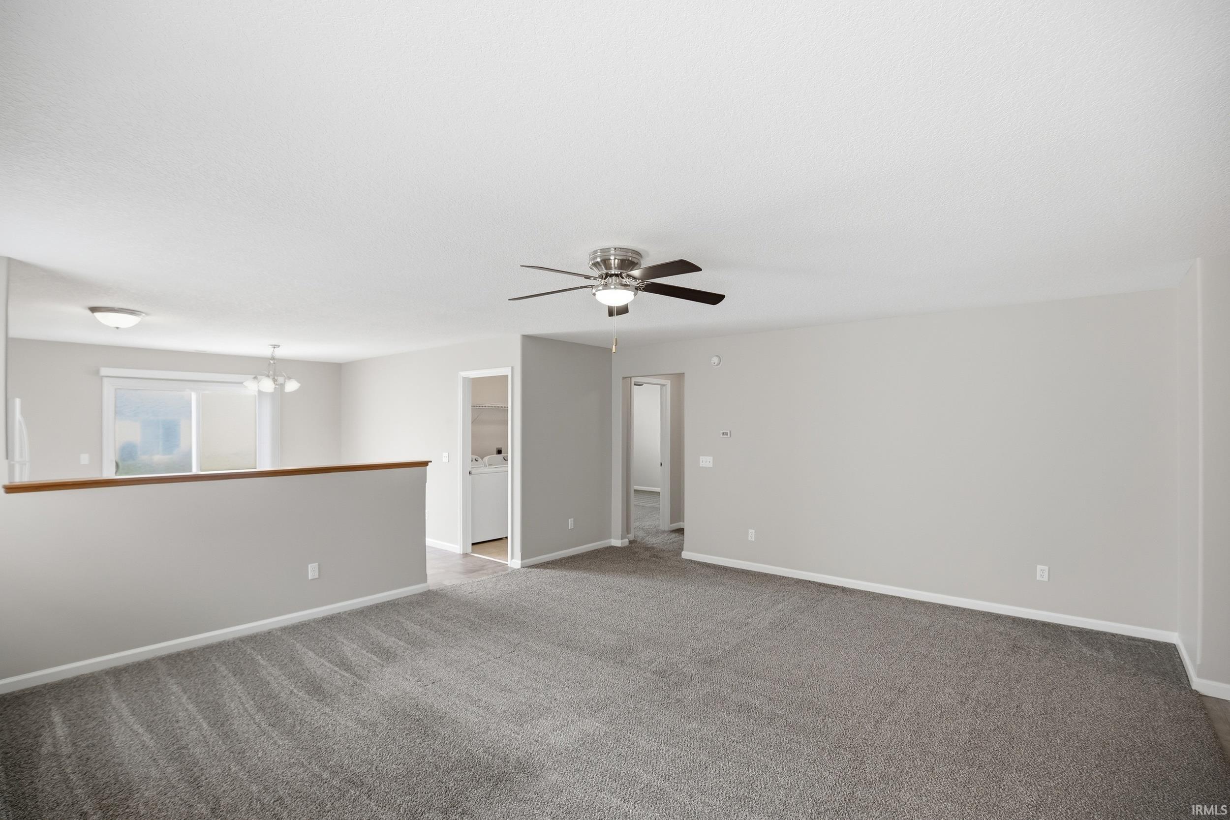 Spacious main living area featuring neutral wall tones, gray carpet, a ceiling fan with integrated lighting, and recessed lighting fixtures