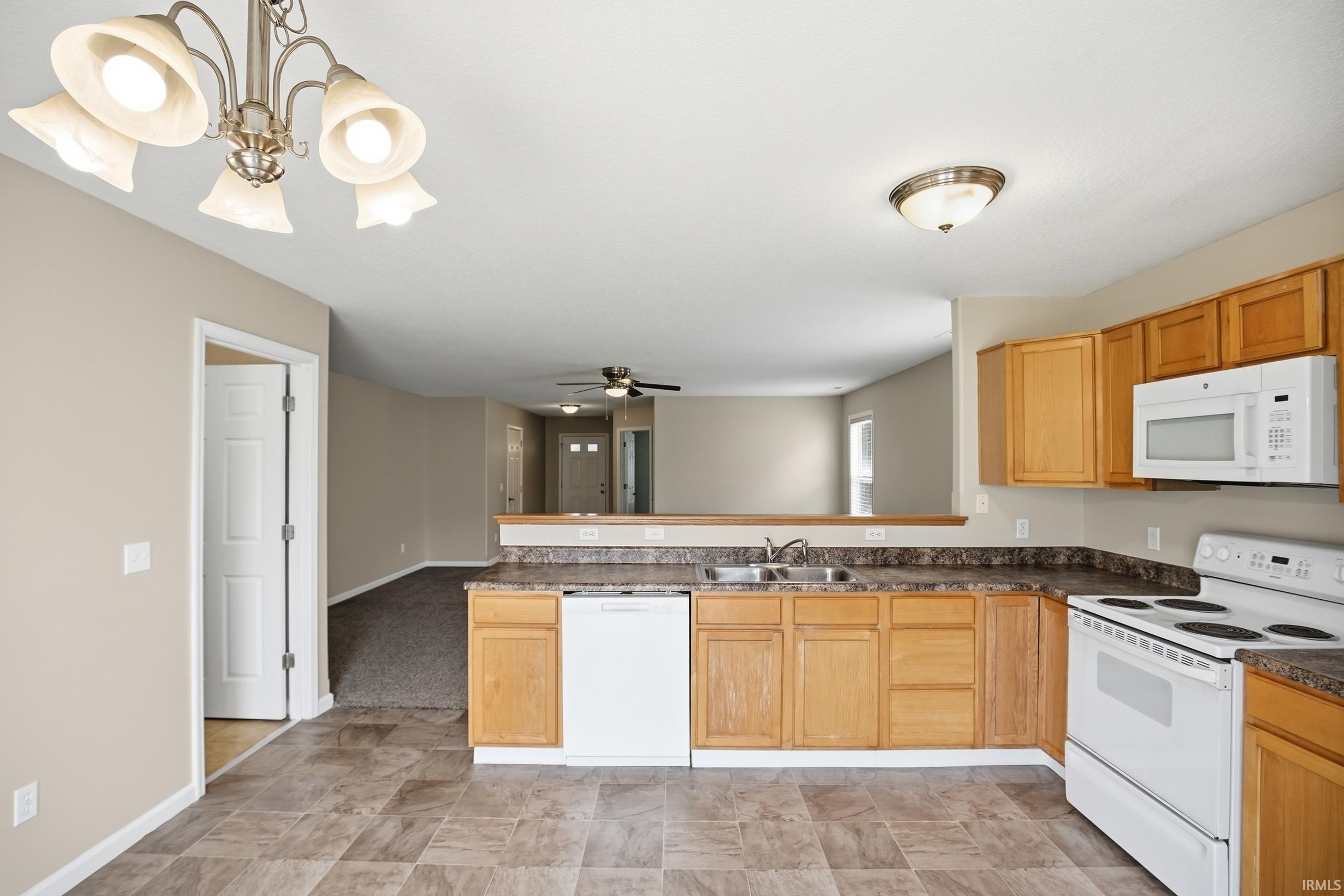 Kitchen featuring wood cabinetry, laminate countertops, a double basin sink, and tile-look flooring