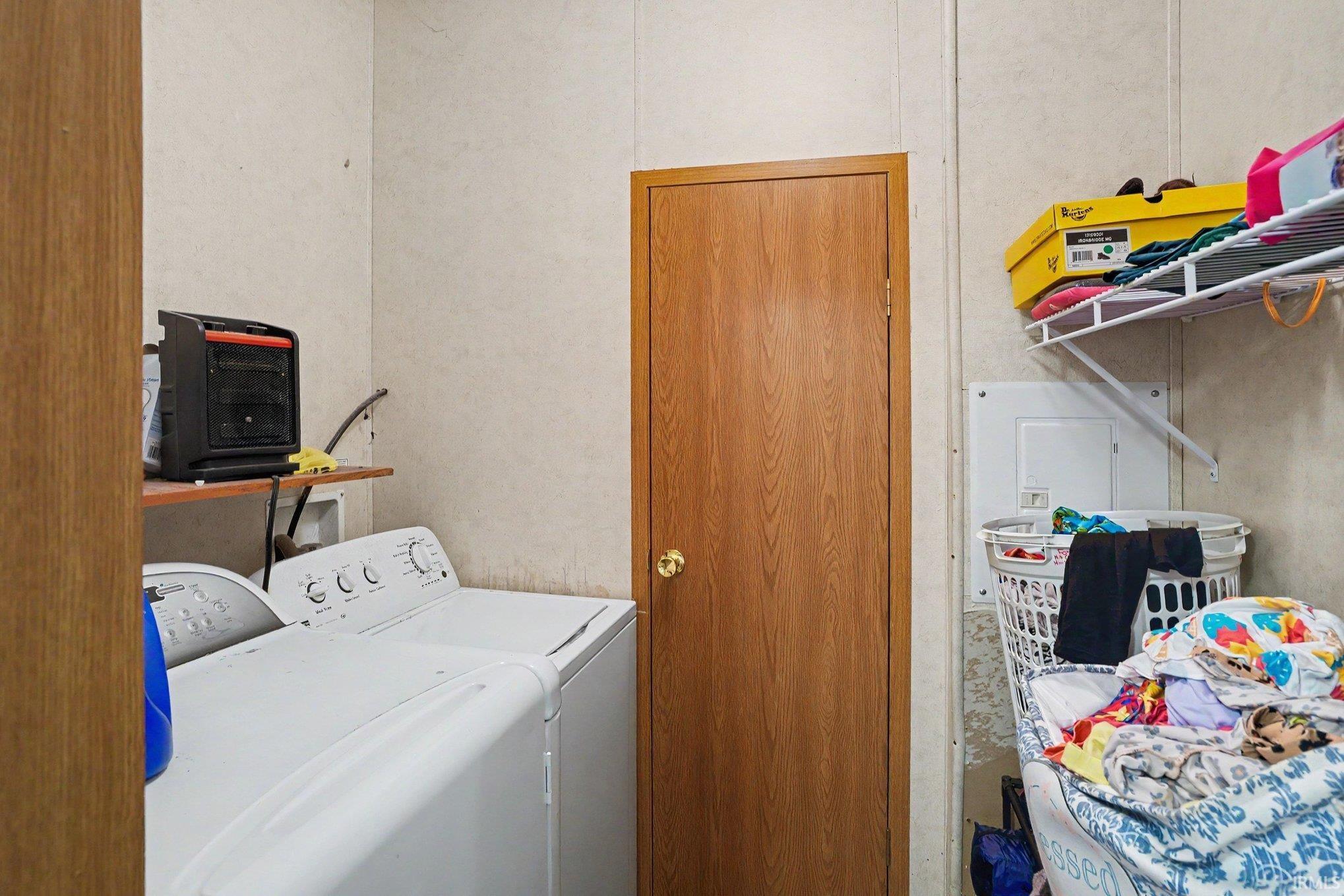 Dedicated laundry area featuring a washer and dryer, a built-in shelving unit, and a wooden door