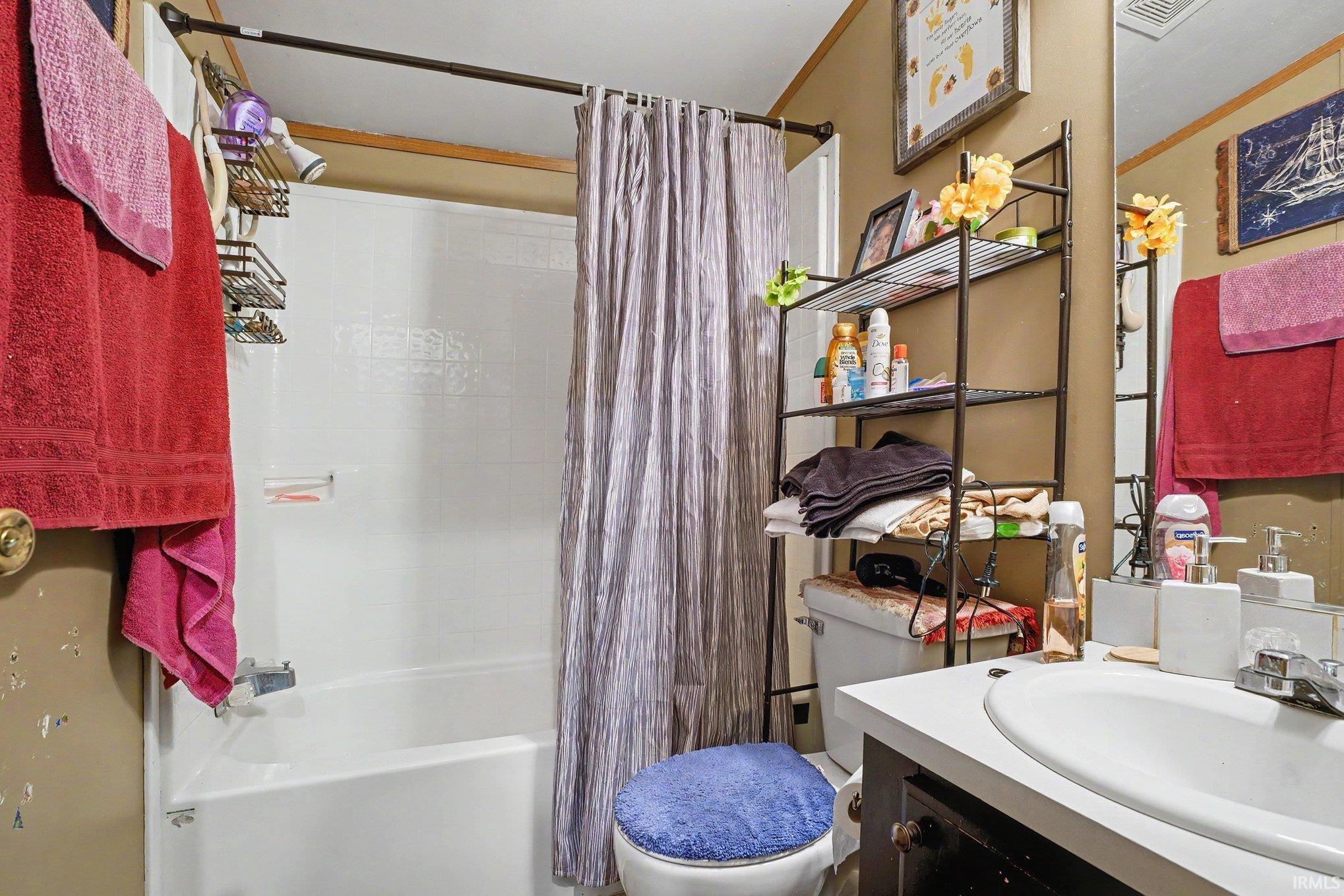 Bathroom featuring a white tub/shower combination, white vanity with integrated sink, and an overhead lighting fixture