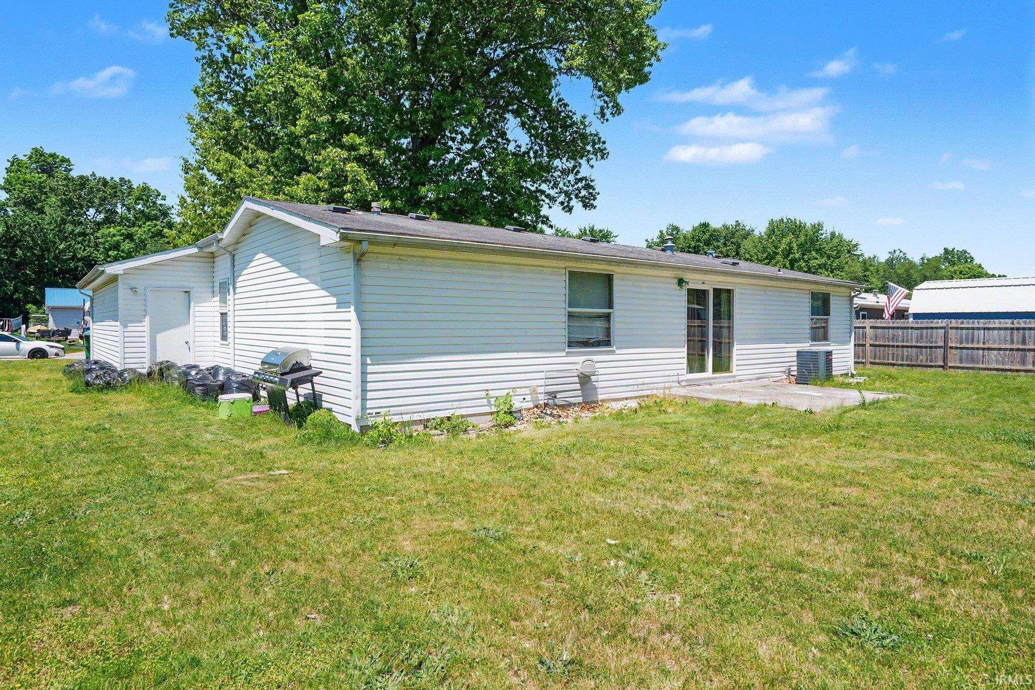 Rear exterior featuring white vinyl siding and a concrete patio