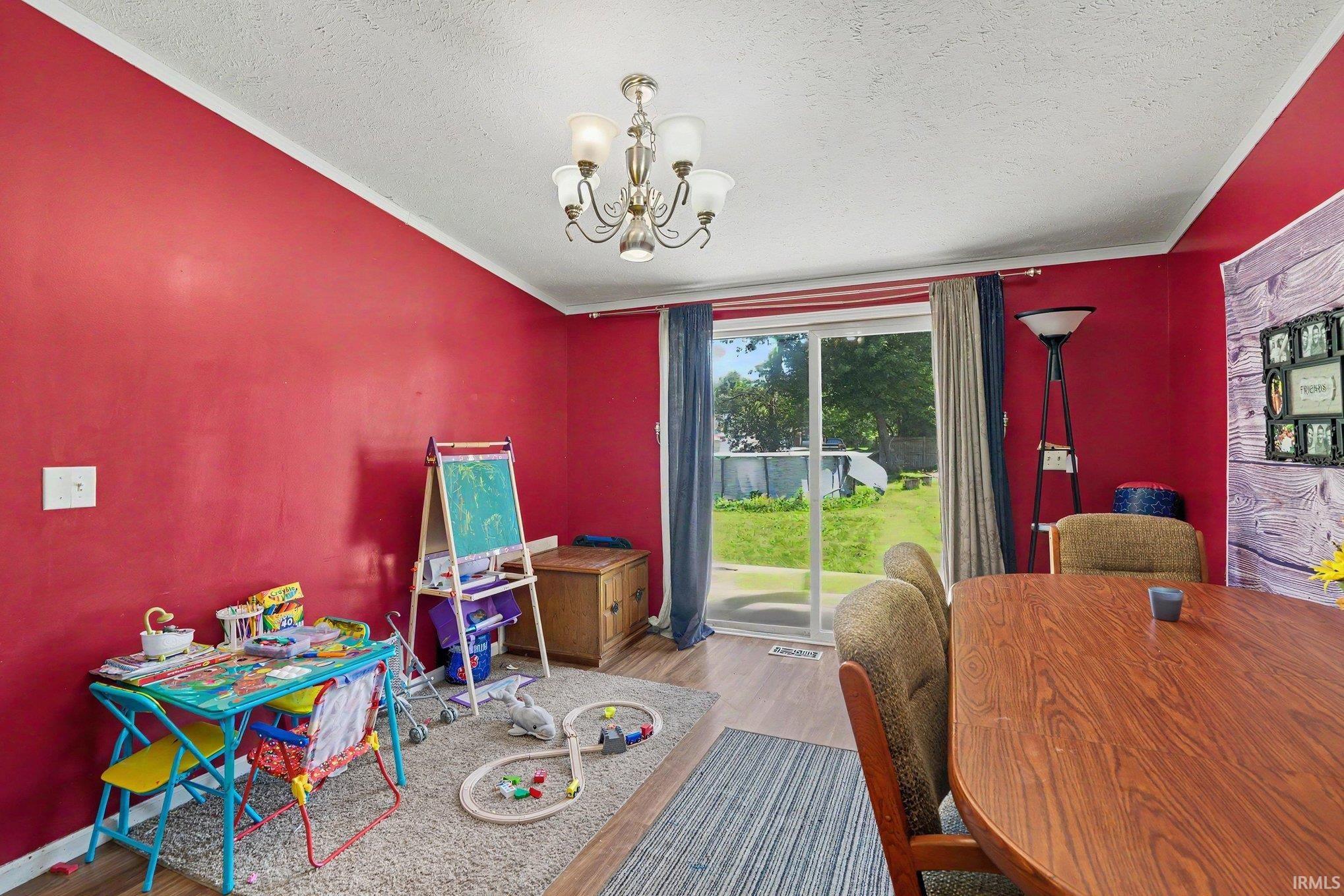 Open room with wood-finish flooring, a ceiling-mounted chandelier, and a sliding glass door providing outdoor access