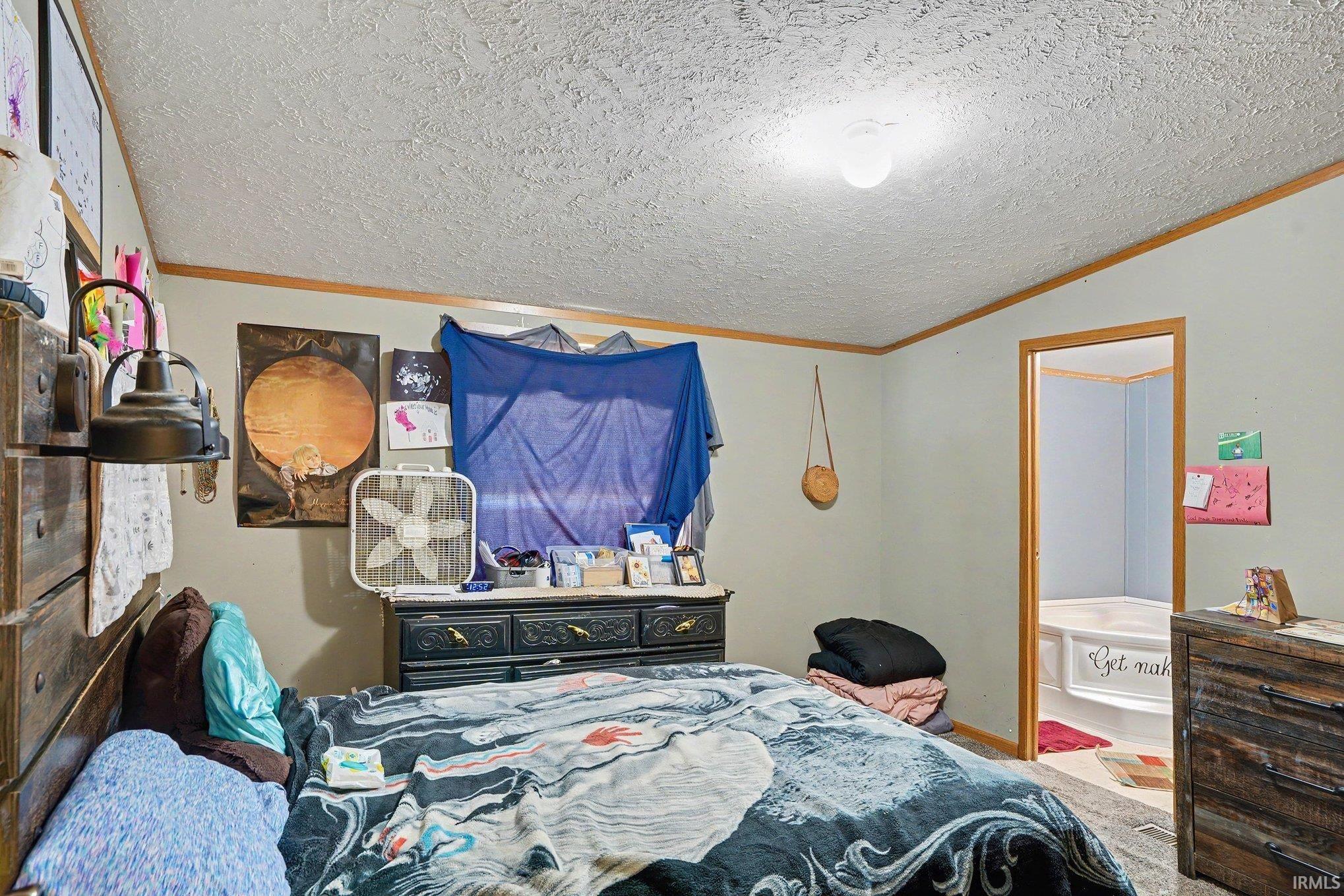 Room featuring light-toned walls, wood-finish trim, and a textured ceiling with a central flush-mount light fixture
