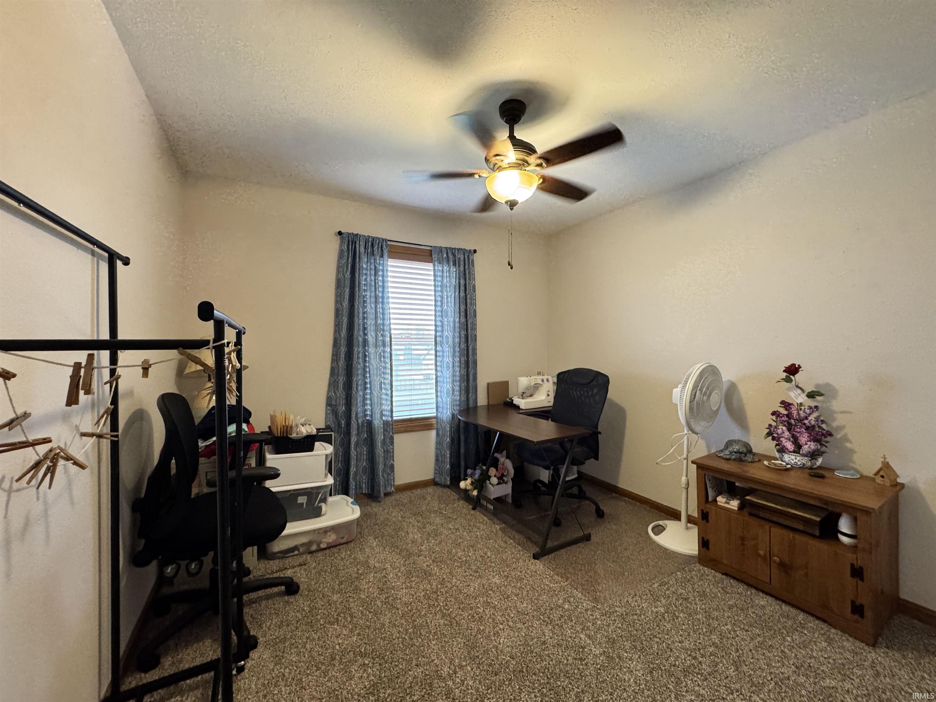 Carpeted room with a vaulted ceiling and ceiling fan with integrated lighting