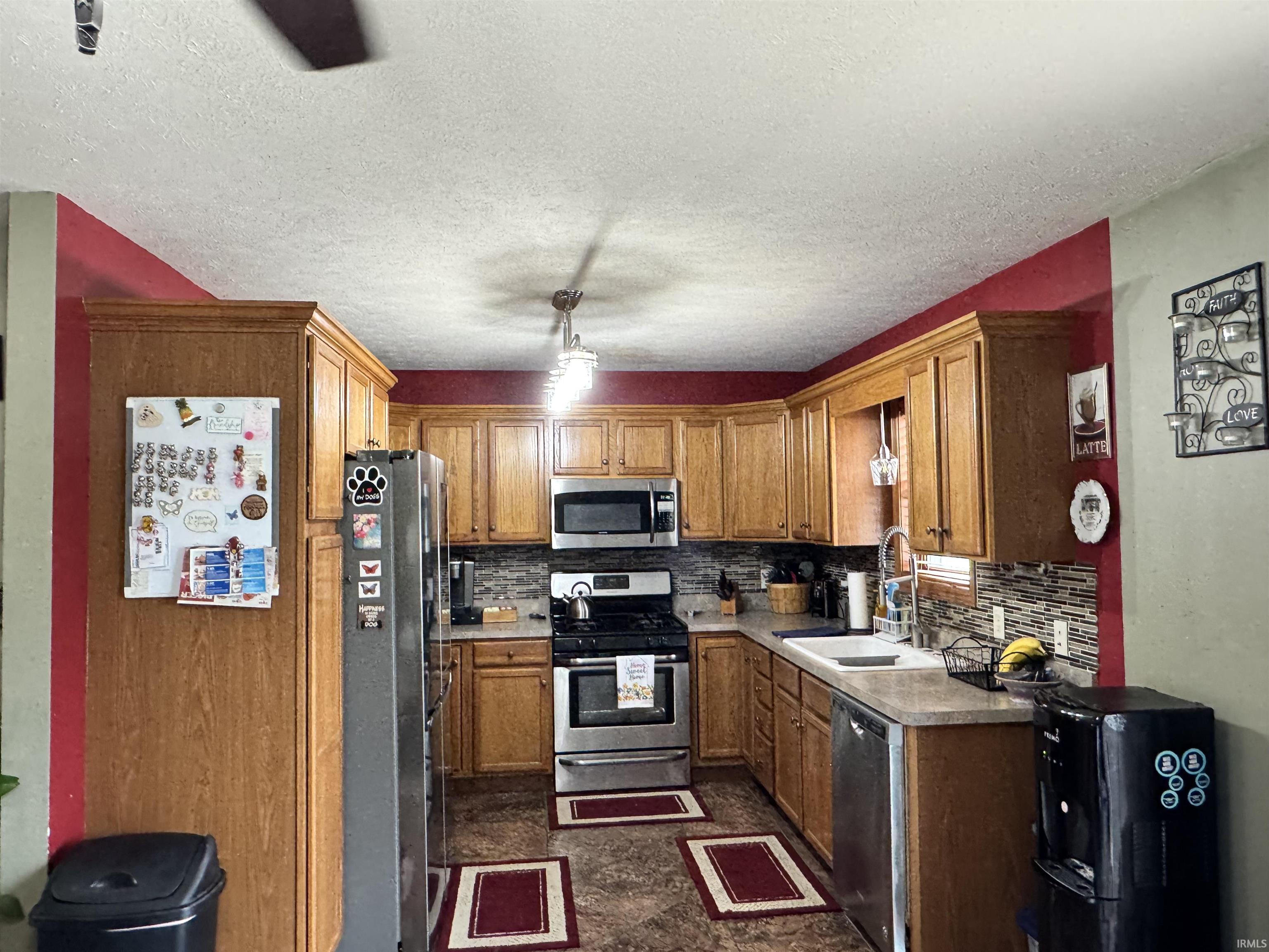 Full kitchen featuring wood cabinetry, stainless steel appliances, a tile backsplash, and a double-basin sink