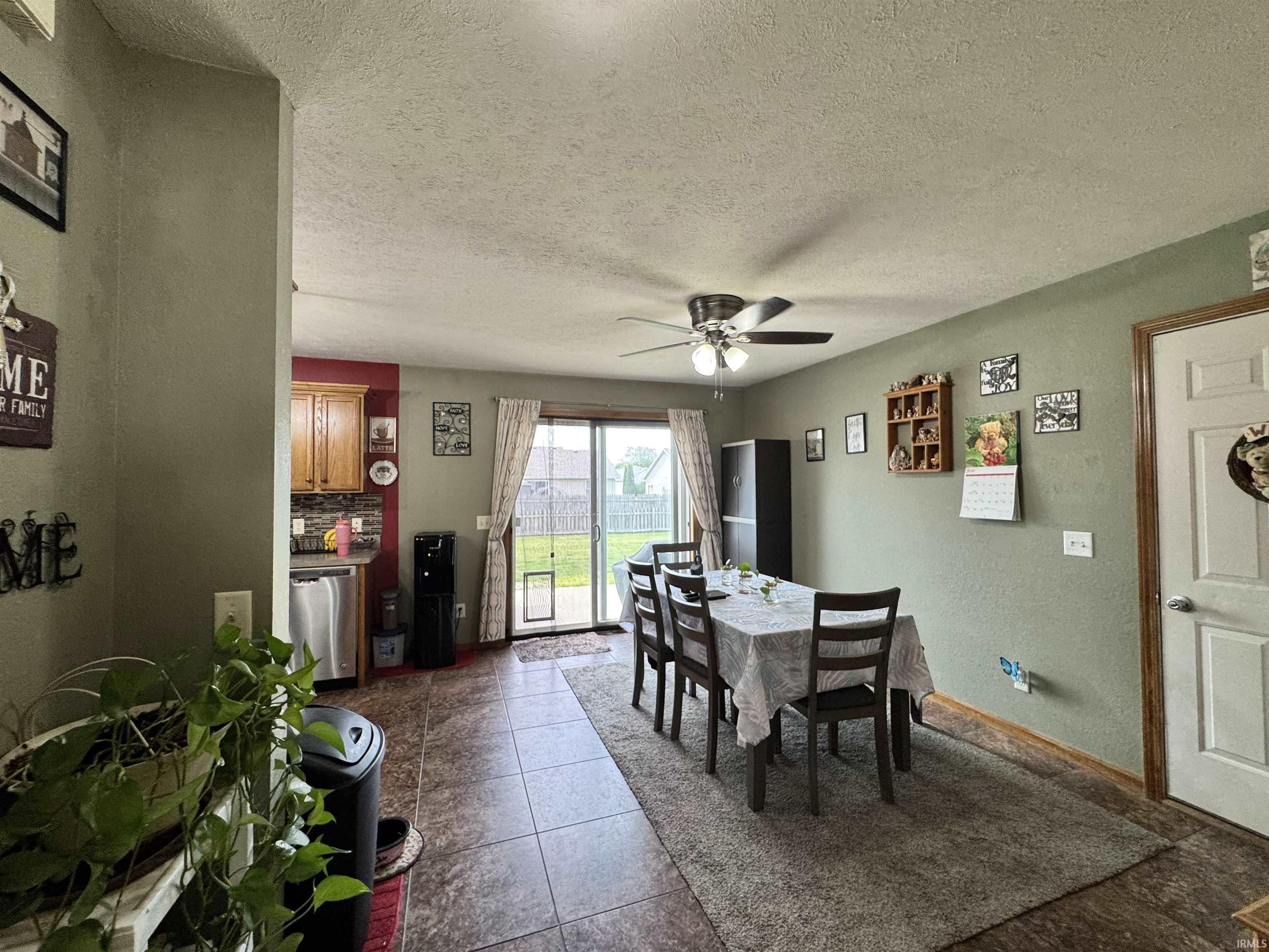 Dining area with a ceiling fan, sliding glass door to the exterior, and tile flooring