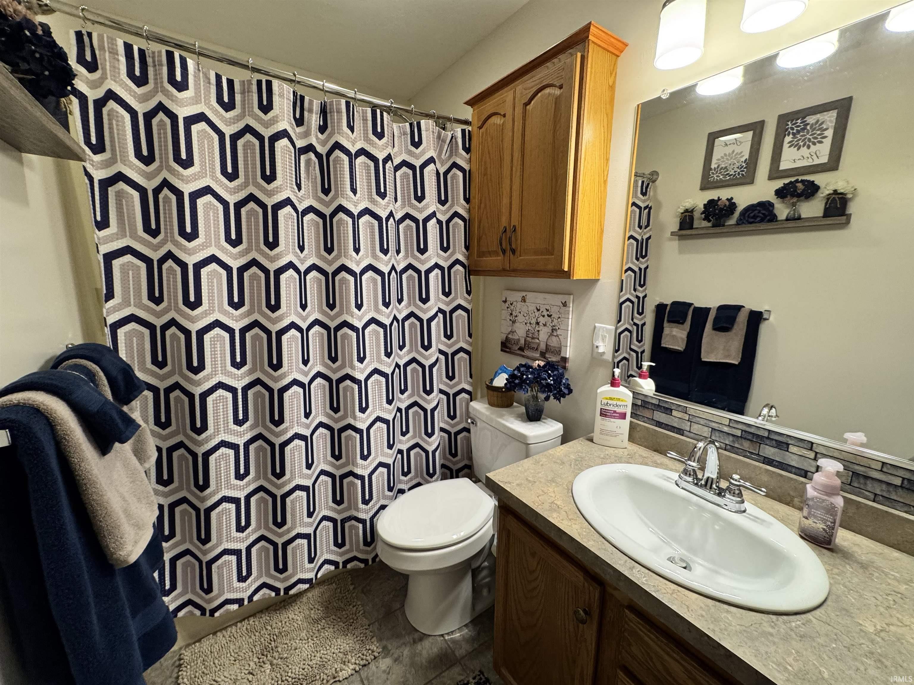 Full bathroom featuring a single vanity, a toilet, and a shower with a patterned curtain
