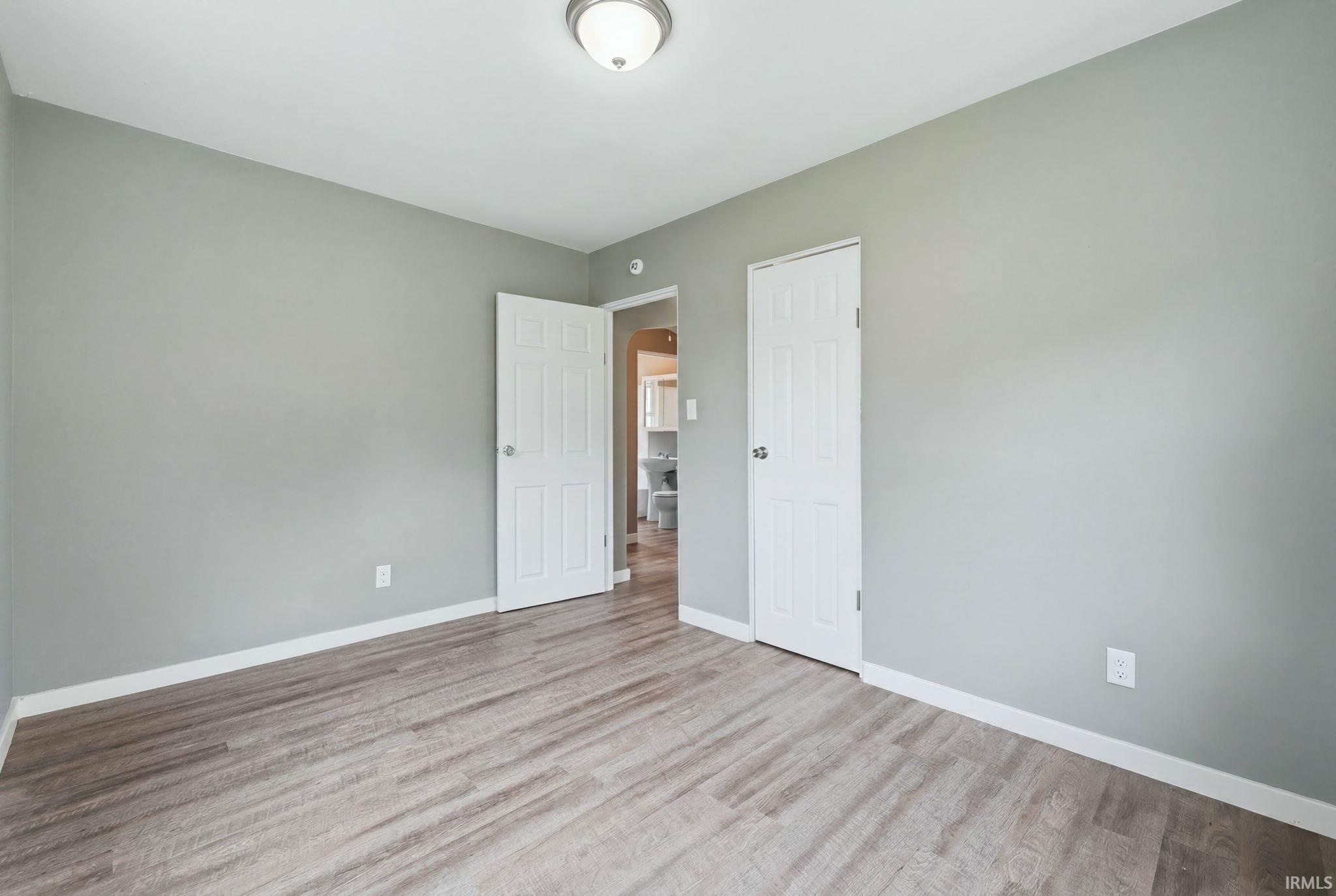 Room featuring wood-finish plank flooring, light gray wall paint, and white baseboards