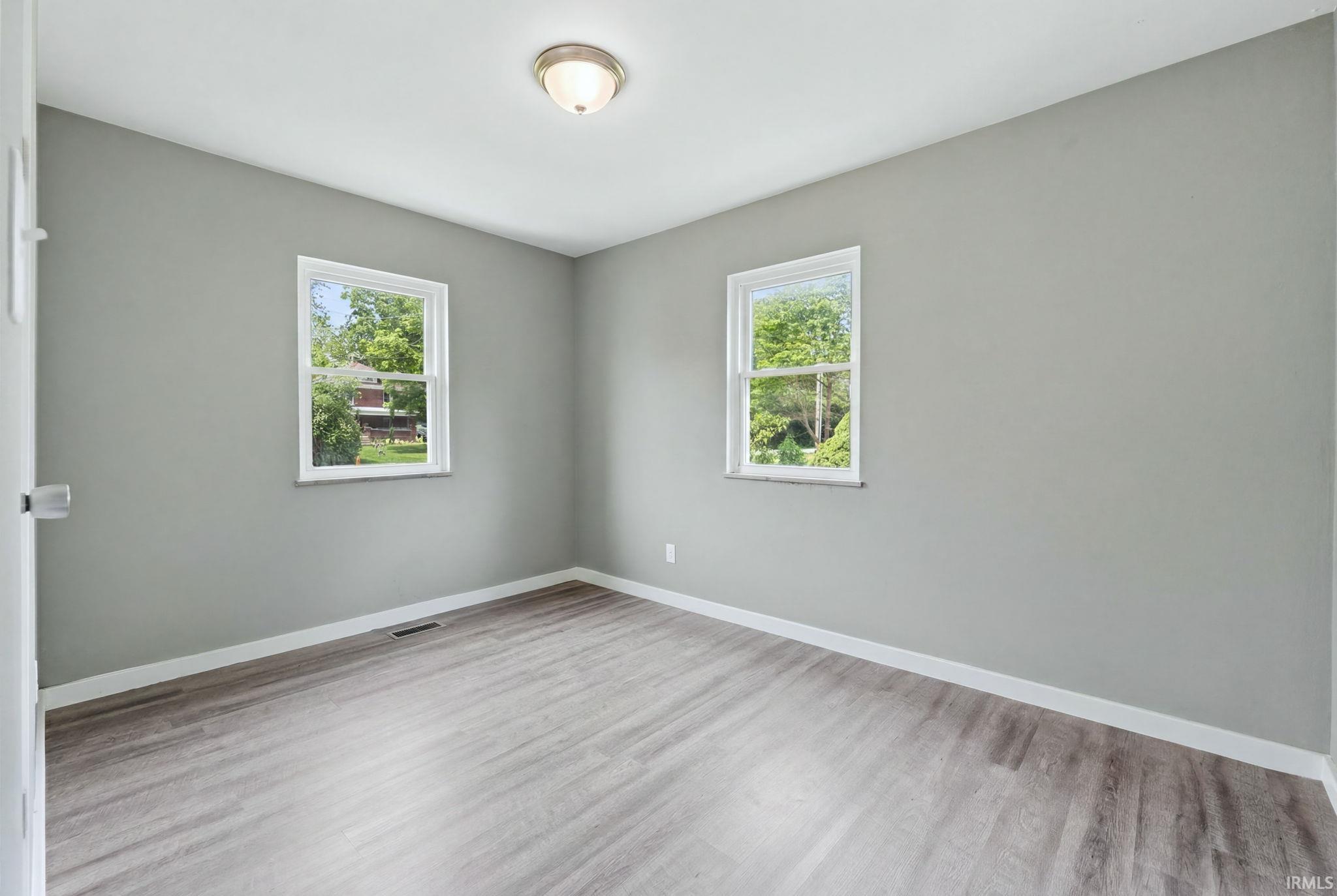 Room with light gray walls, white trim, and wood-finish flooring